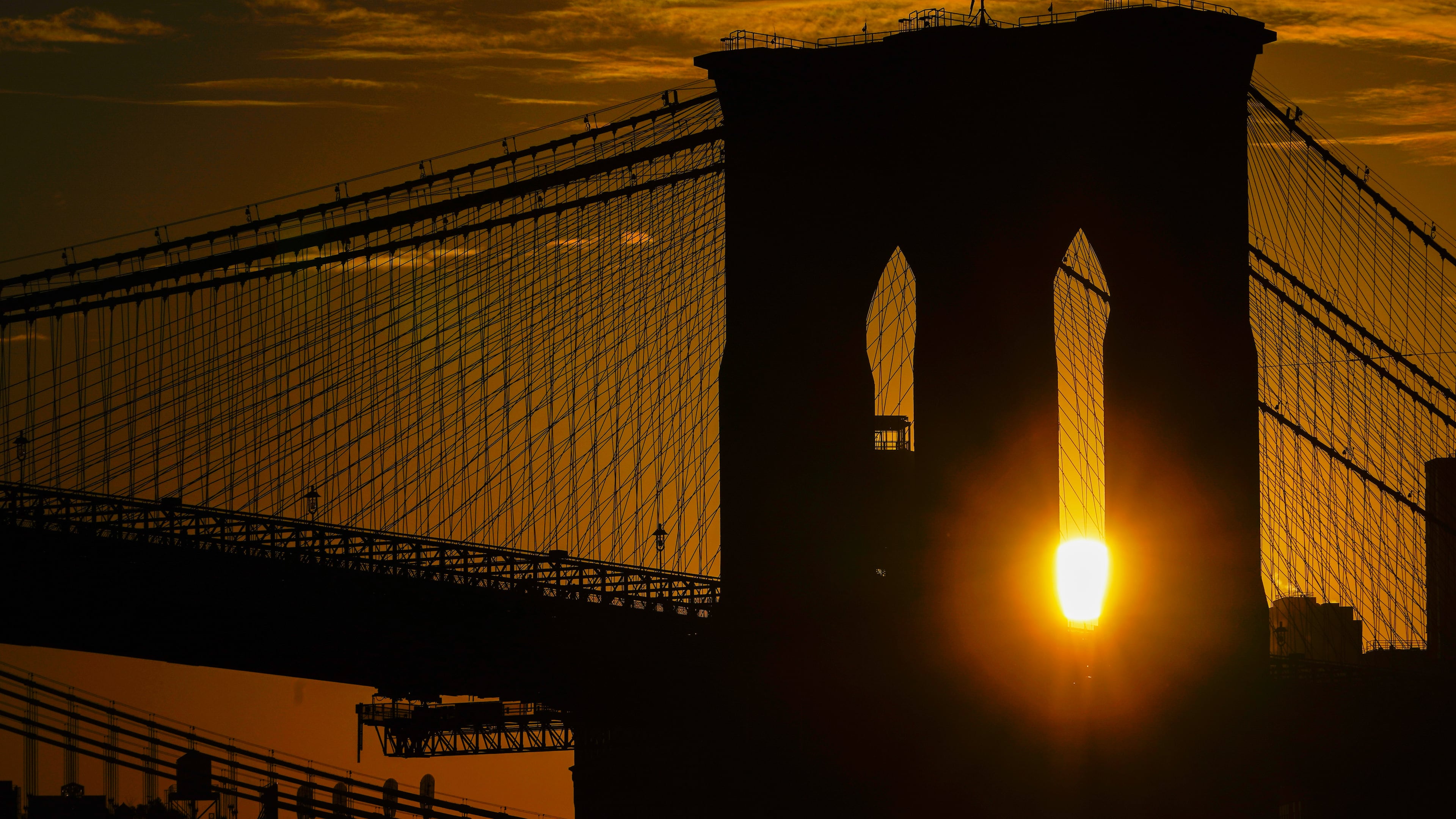 FILE - The sun rises behind the Brooklyn Bridge on Oct. 11, 2023, in New York. (AP Photo/Kiichiro Sato, File)