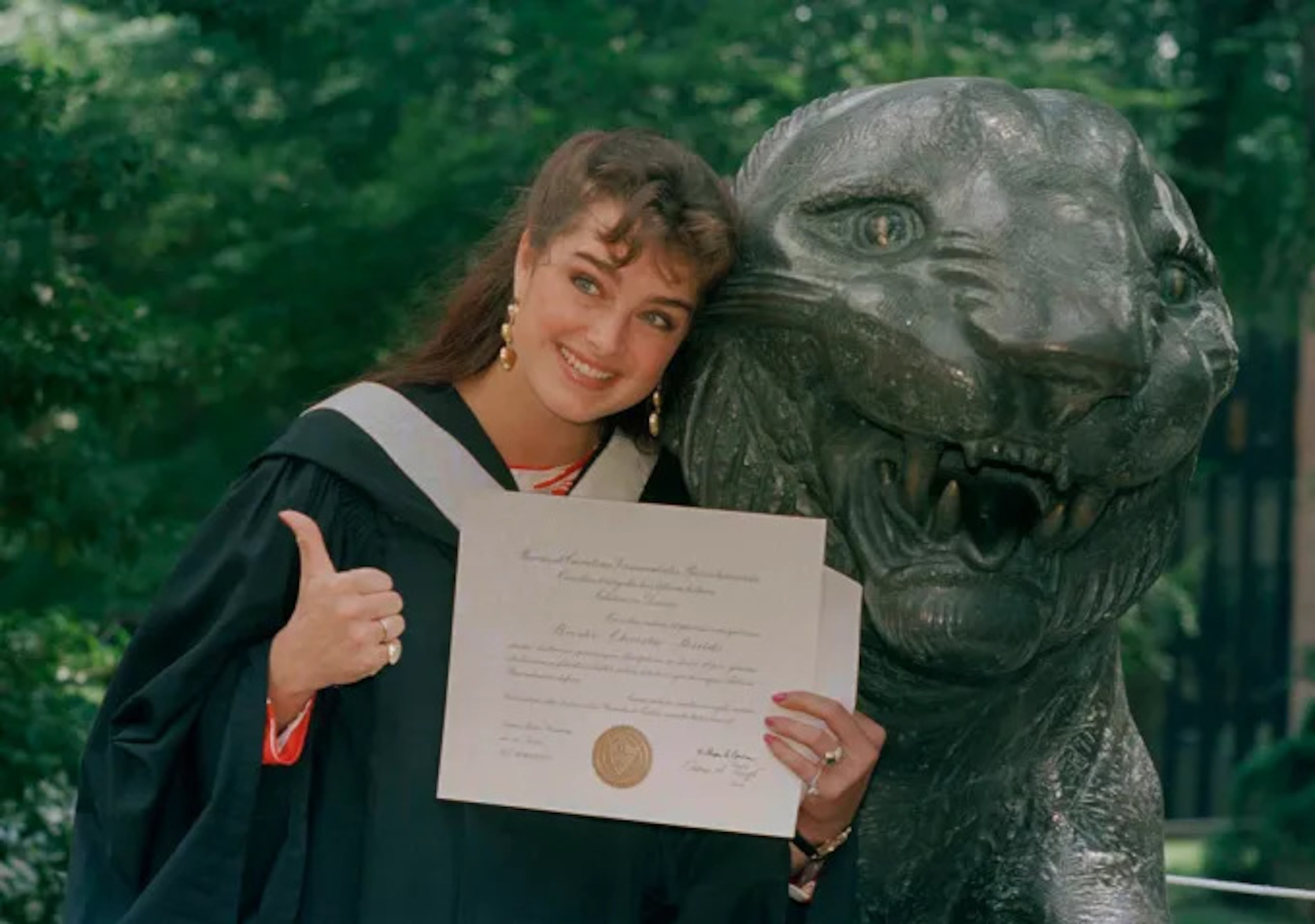 Actress Brooke Shields gives the thumbs-up in her cap and gown as she shows her diploma during graduation ceremonies at Princeton University. She graduated from the New Jersey institute in 1987. AP