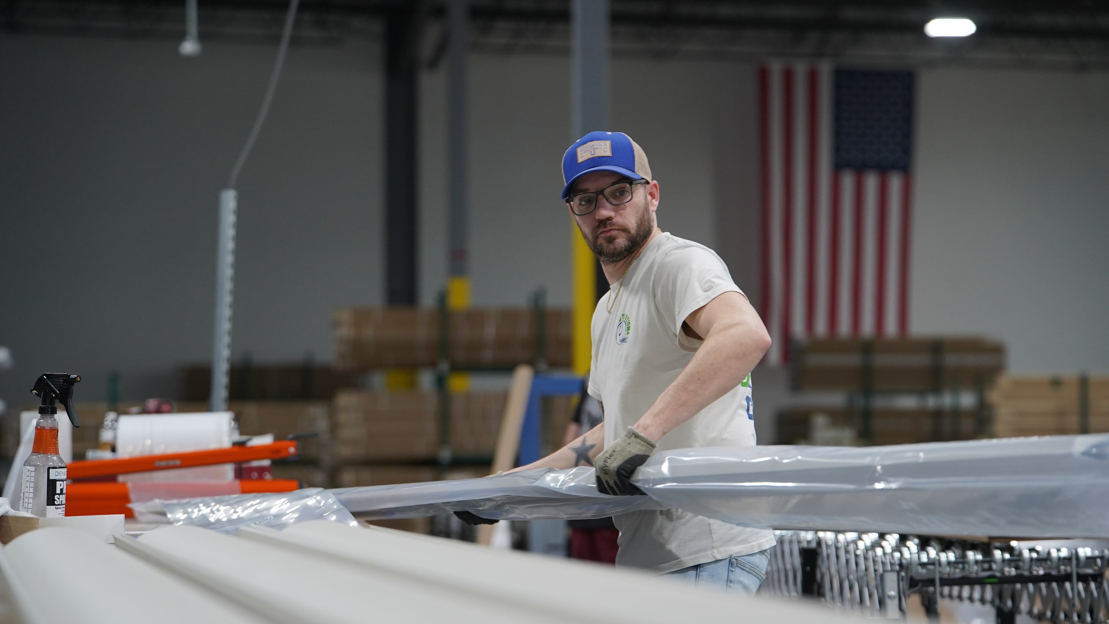 A worker lifts an aluminum beam on the factory floor at The Luxury Pergola, a company that manufactures aluminum pergolas, on Friday, Feb. 20, 2026, in Noblesville, Ind. (AP Photo/Obed Lamy)
