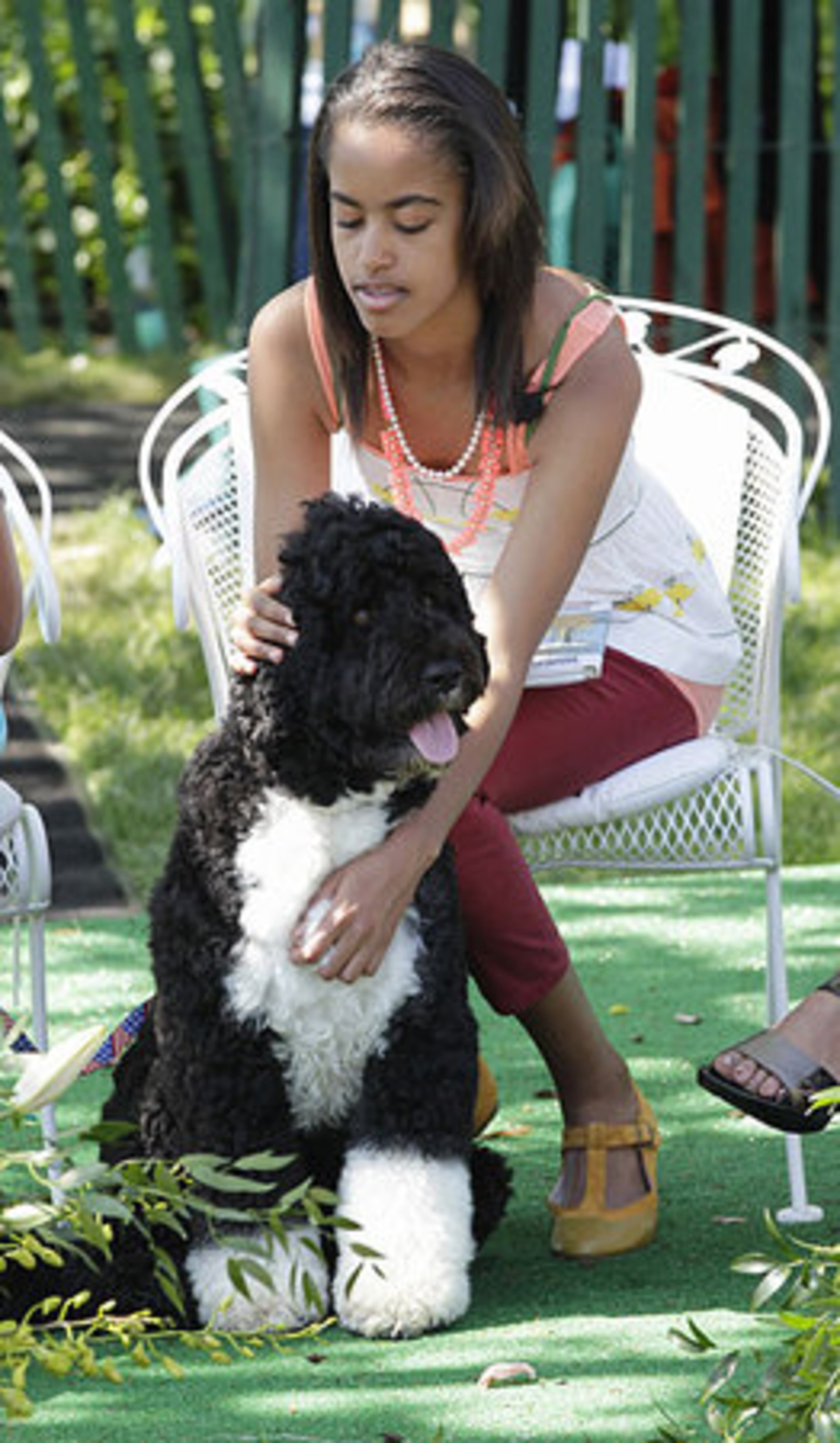 The presiden't daughter, Malia Obama, caresses Bo, the family dog, during the Easter Egg Roll festivities at the White House in Washington, Monday, April 25, 2011.