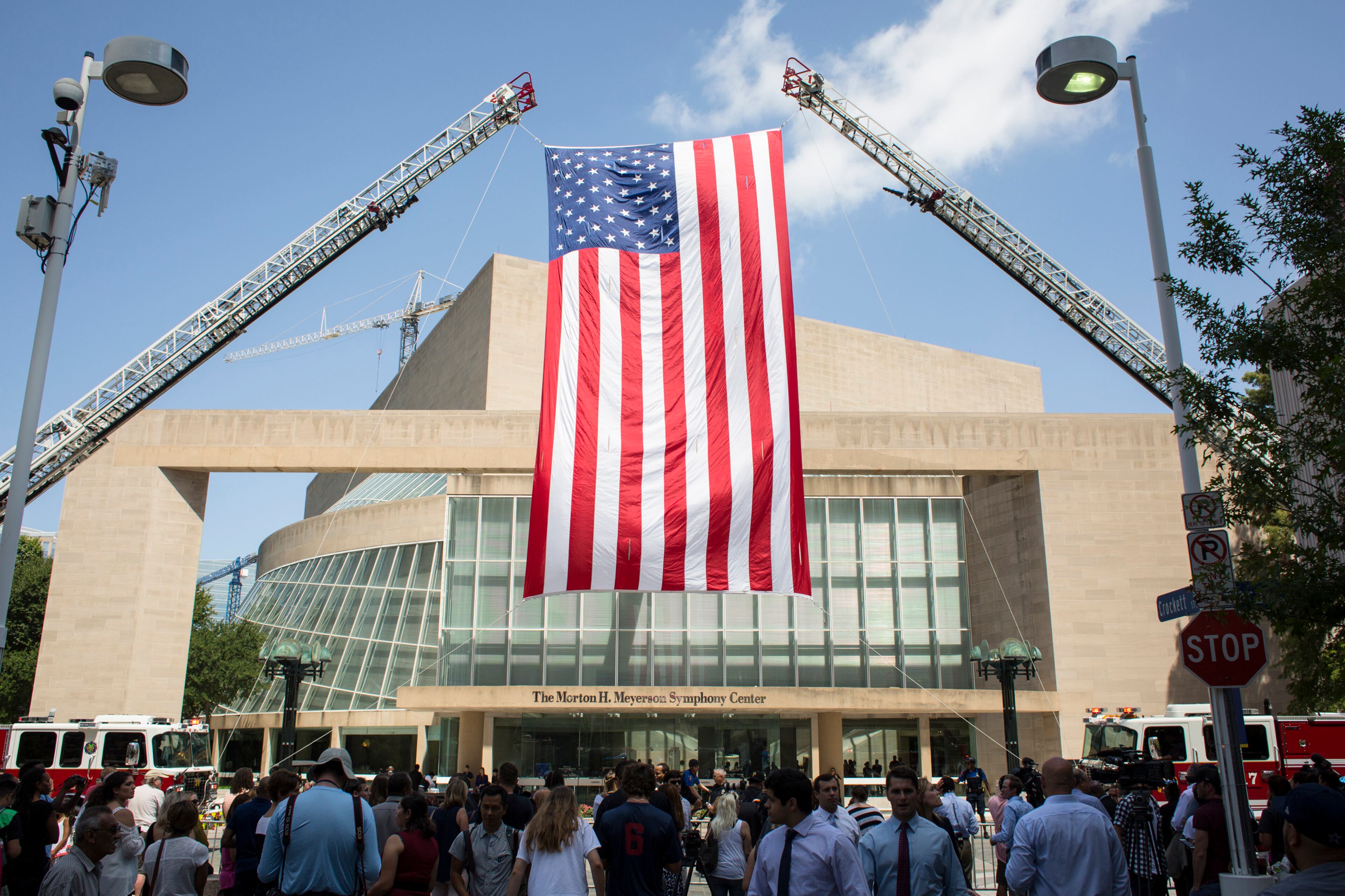 A U.S. flag hangs outside of the Morton H. Meyerson Symphony Center before an interfaith memorial service for the five police officers killed on July 7 by Micah Xavier Johnson, in Dallas, July 12, 2016. President Barack Obama and former President George W. Bush will speak at the memorial. (David Ryder/The New York Times)