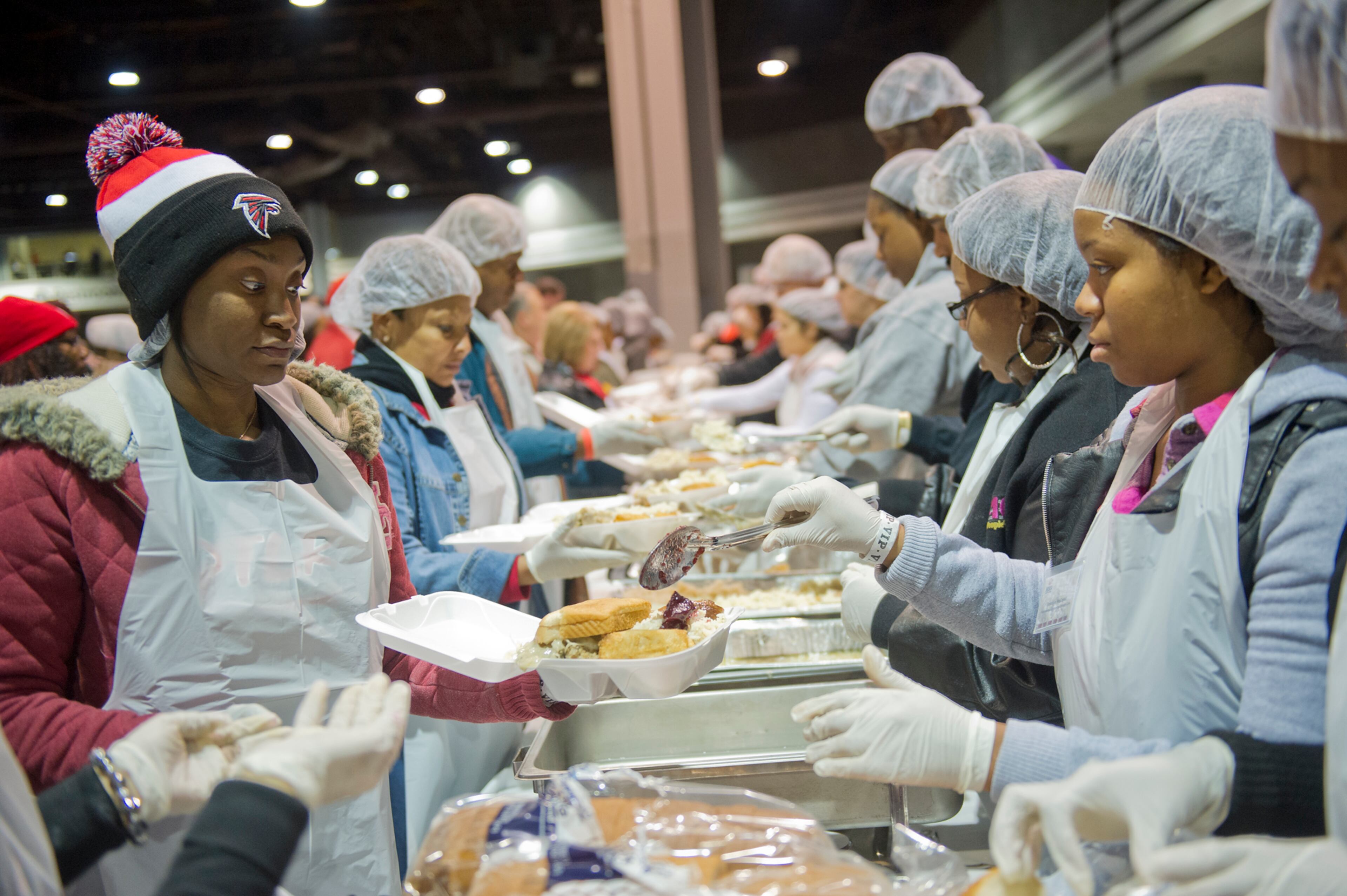 Naquonna Glenn (left) carries trays of food down a line of volunteers as Katera Samuel spoons cranberry sauce onto them during the Hosea Feed the Hungry and Homeless annual Thanksgiving meal at the Georgia World Congress Center in Atlanta on Nov. 28, 2013. In addition to eating a complete meal, the more than 20,000 people attending were given the opportunity to take showers and receive new clothing, medical care, flu shots and other services at no cost.