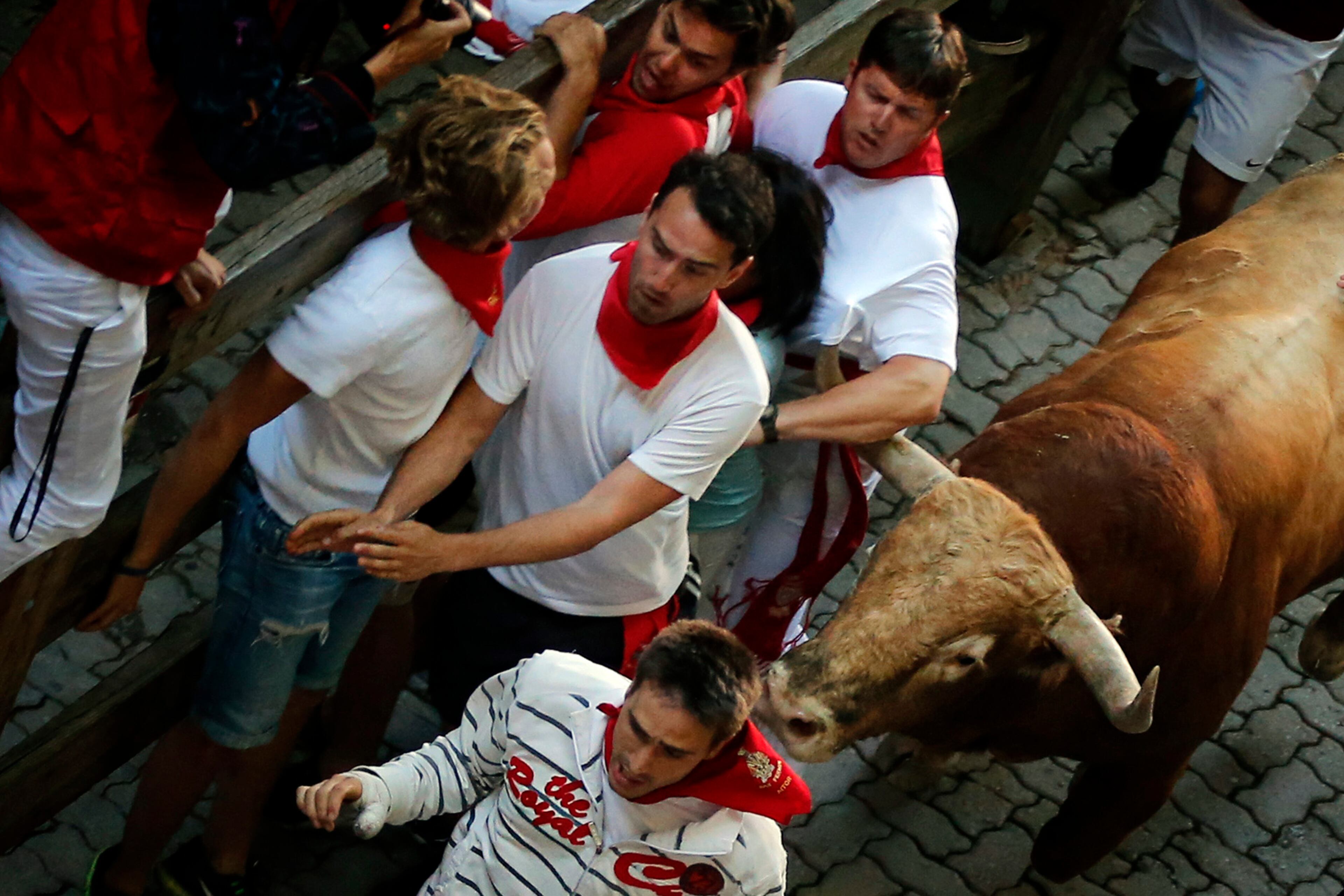 A Garcigrande's ranch fighting bull hook the shirt of a reveler during the daily morning running of the bulls of the San Fermin festival in Pamplona, Spain, Monday, July 13, 2015. Revelers from around the world arrive in Pamplona every year to take part on some of the eight days of party and the running of the bulls. (AP Photo/Daniel Ochoa de Olza)