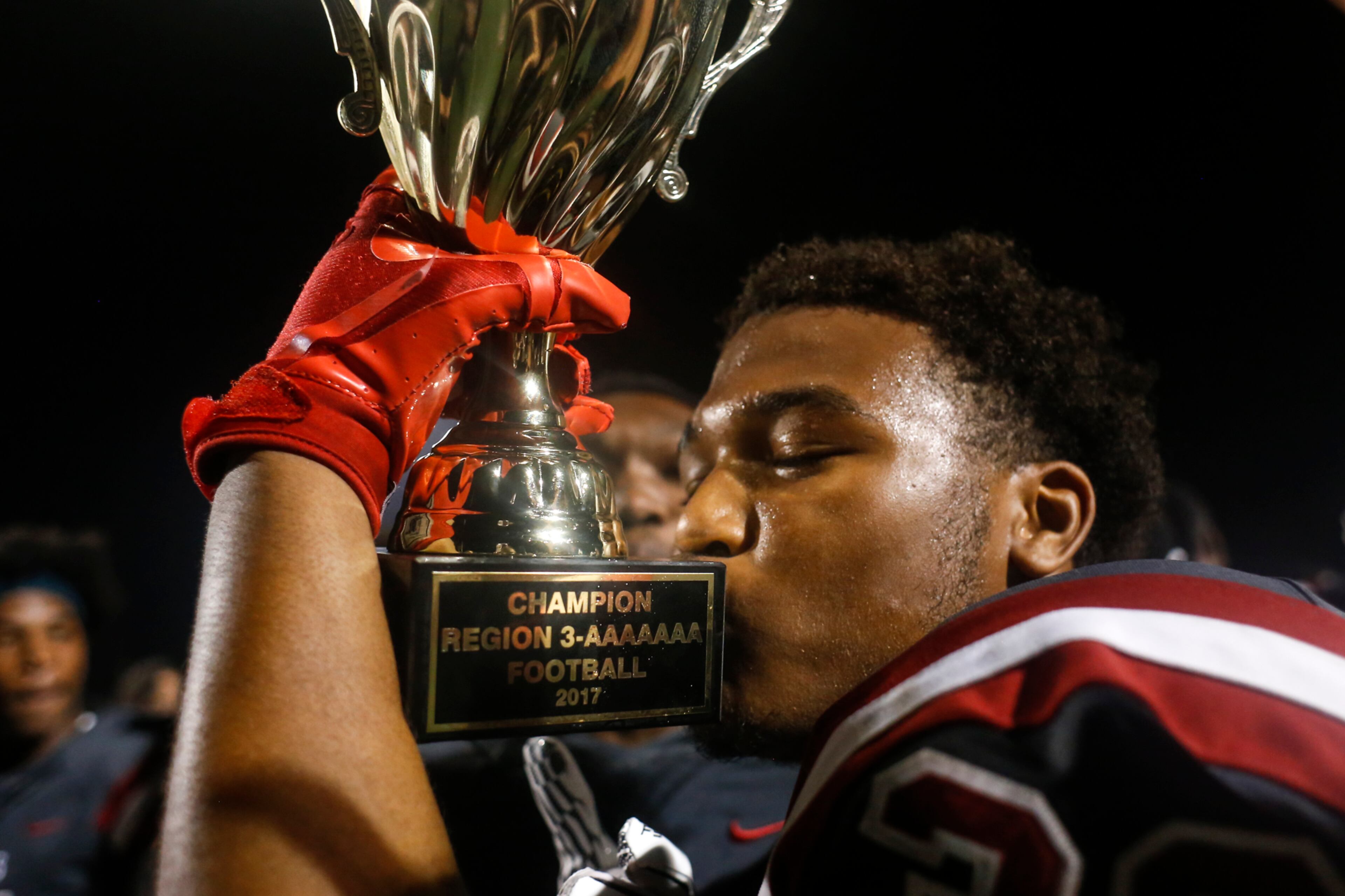 Hillgrove linebacker Jordan Butler (30) kisses the region championship trophy after the team's 14-7 victory over McEachern Friday. Hillgrove ended McEachern's two-year reign as region champions and snapped their 15-game winning streak in region games. (CASEY SYKES, CASEY.SYKES@AJC.COM)