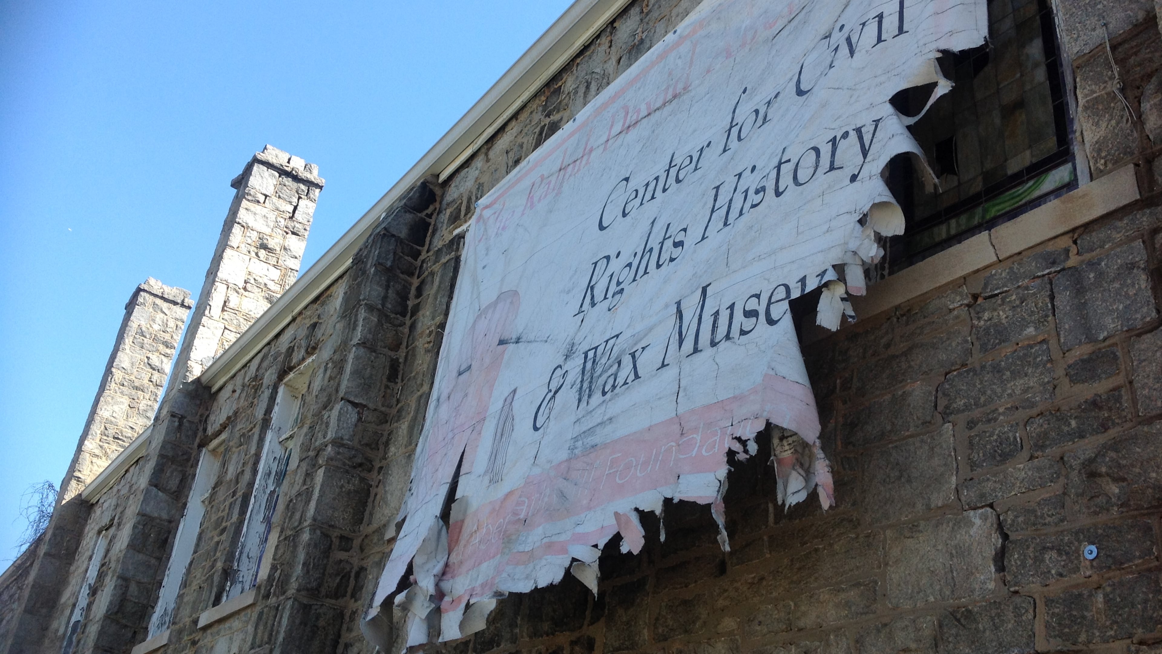 A tattered sign hangs delicately from the West Hunter church. The sign announced a civil rights museum that never came.