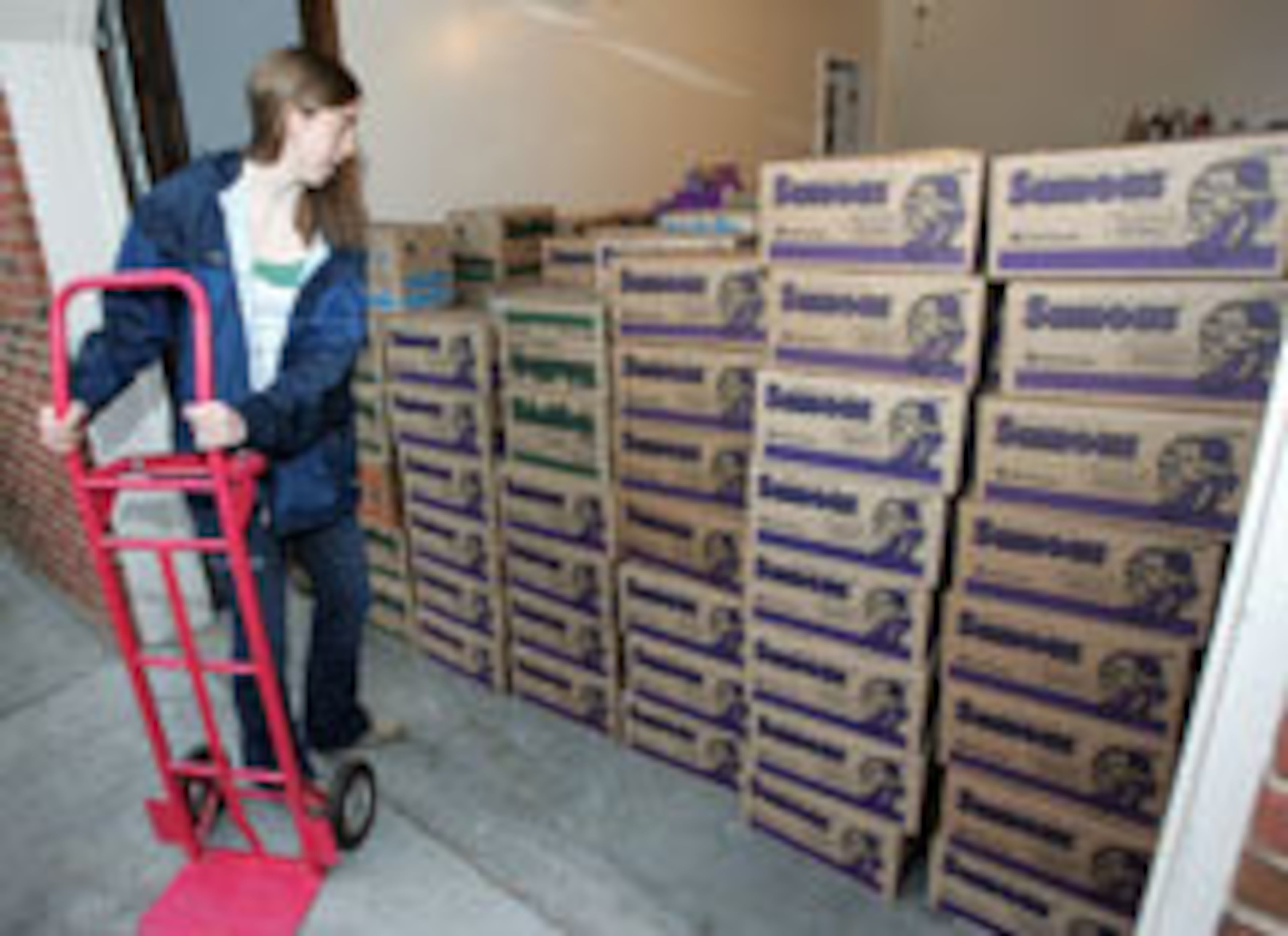 Ginny Fahs uses a dolly to start to load boxes of cookies.