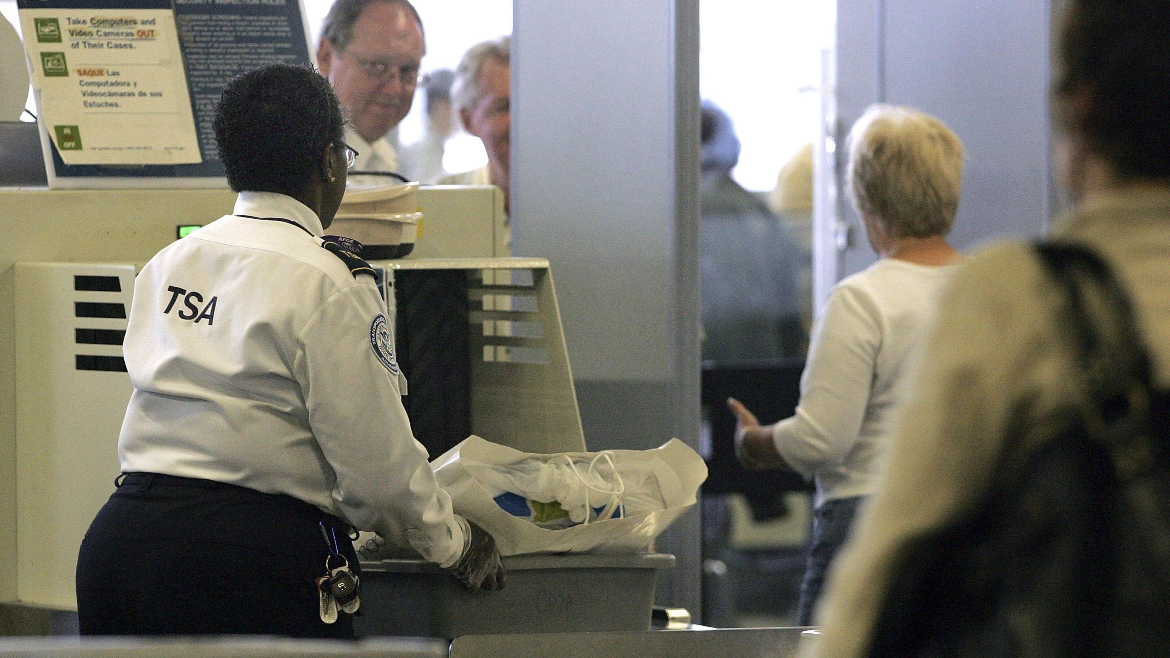 A TSA worker sends a traveler's belongings through an x-ray machine at a security checkpoint. As the partial government shutdown moves into its 25th day, more TSA workers are calling out because they're not getting paid.
