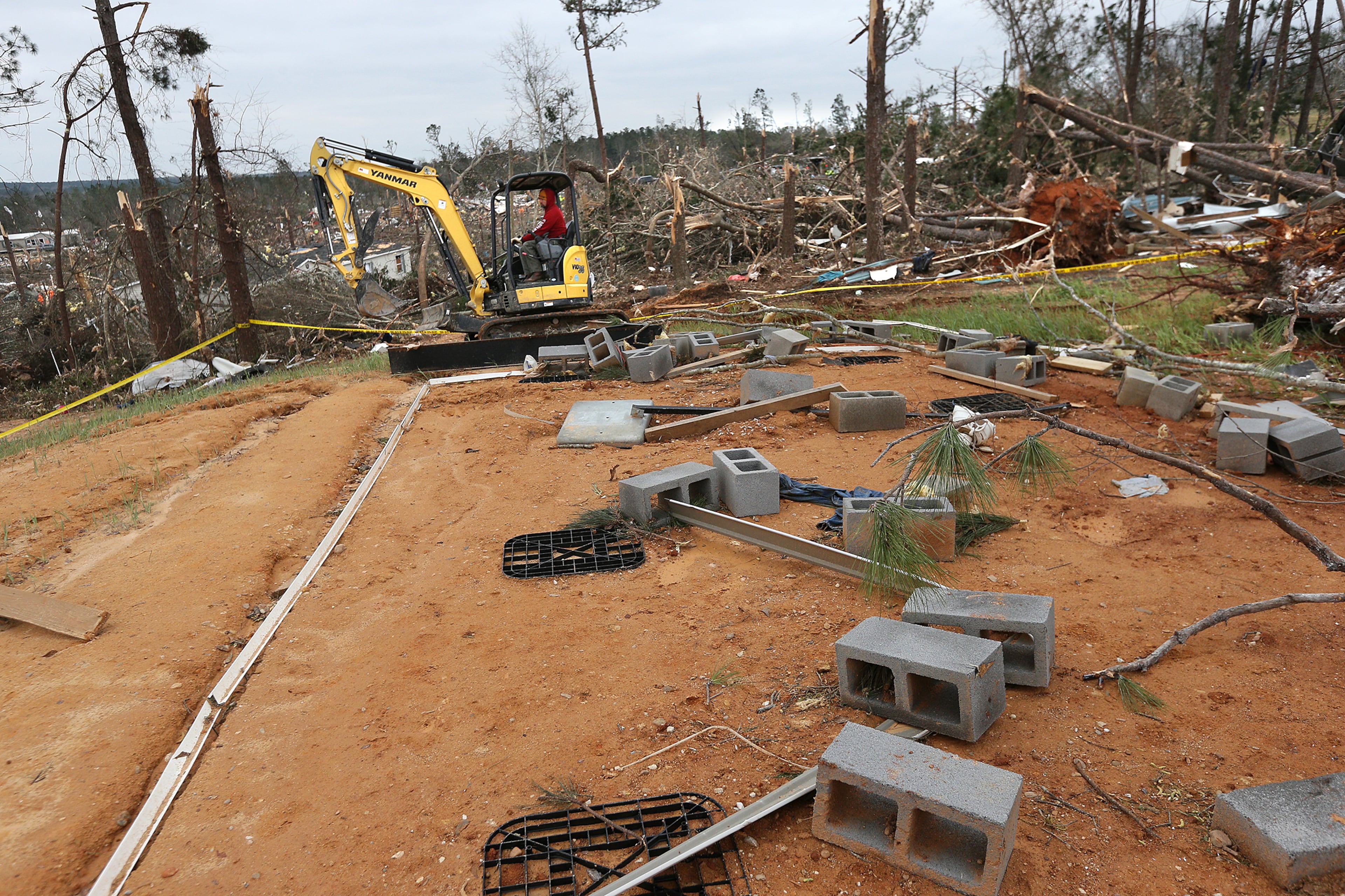 A worker cleaning up debris passes by the foundation of what remains of a home along Lee Road 38 after a F-3 tornado on Monday, March 4, 2019, in Beauregard. Twenty-three people -- including a six-year-old -- were killed by a storm Sunday, though that number is expected to climb, Lee County Sheriff Jay Jones told reporters Monday morning. The destruction area is at least a half a mile wide and at least a mile long, he added. Curtis Compton/ccompton@ajc.com