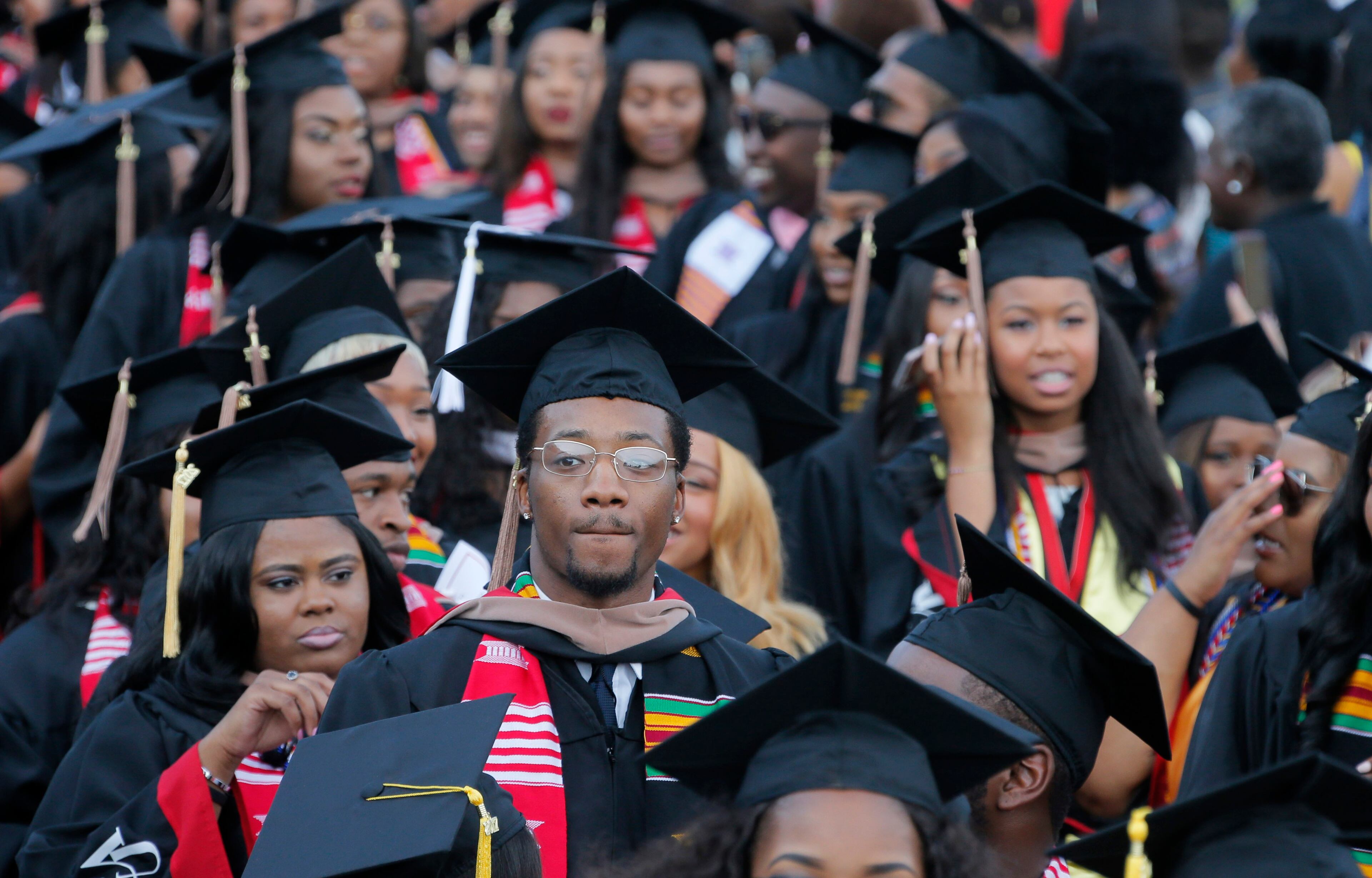 5/22/17 - Atlanta - Some graduates look toward the stands and family members, while others are on their phones as they enter during the Processional. Clark Atlanta University's Panther Stadium was the site of their 28th annual Commencement. Businessman William Pickard gave the commencement address. Rev. Jesse Jackson, who received an honorary degree also spoke. Panther Stadium, BOB ANDRES /BANDRES@AJC.COM