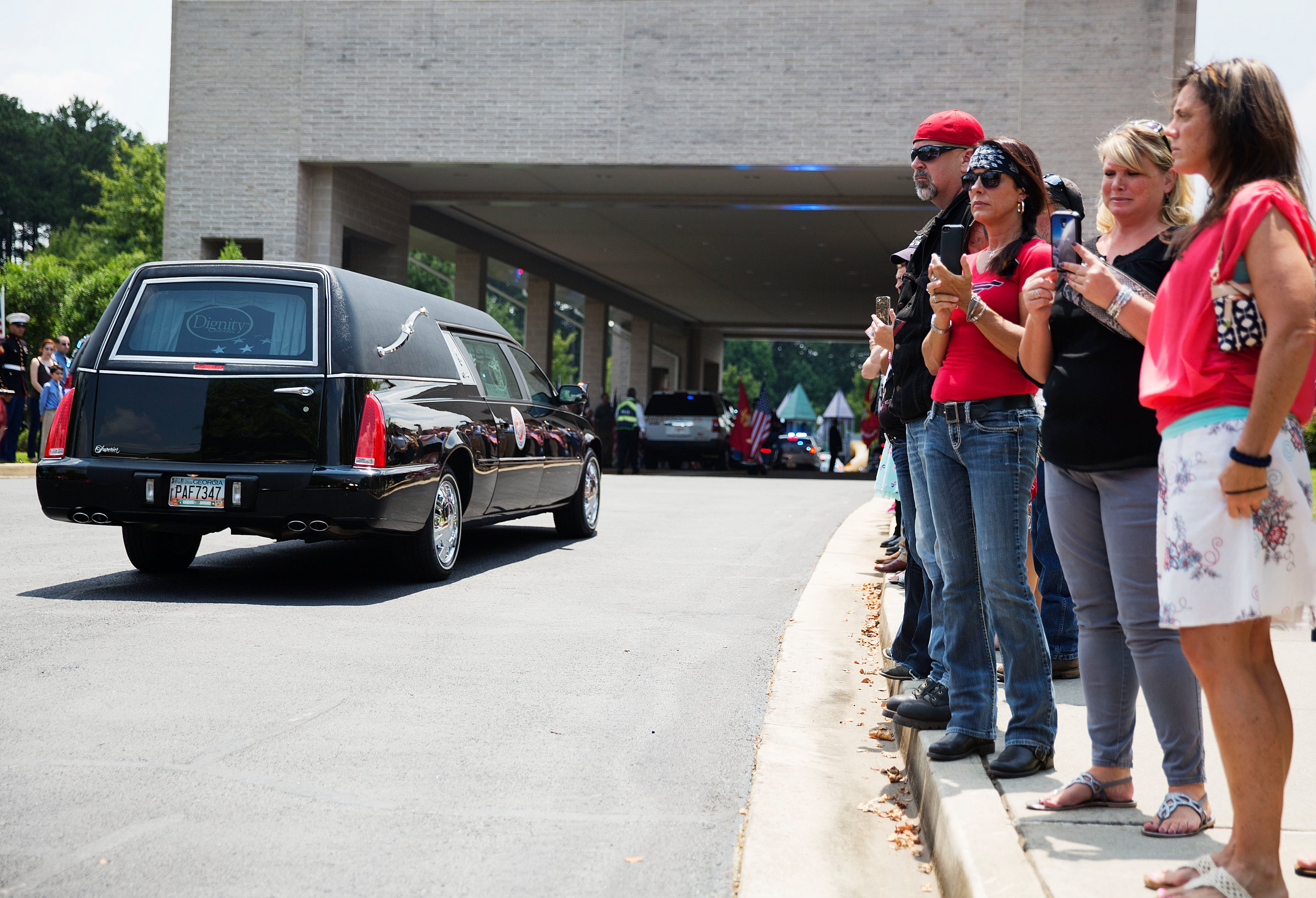 Mourners watch as a hearse carrying the casket of Lance Cpl. Squire Wells, known as "Skip," arrives for his funeral service Sunday, July 26, 2015, in Woodstock, Ga. The 21-year-old Wells was killed July 16 when a man opened fire at two military facilities before being killed by police in Chattanooga, Tenn. (AP Photo/David Goldman)