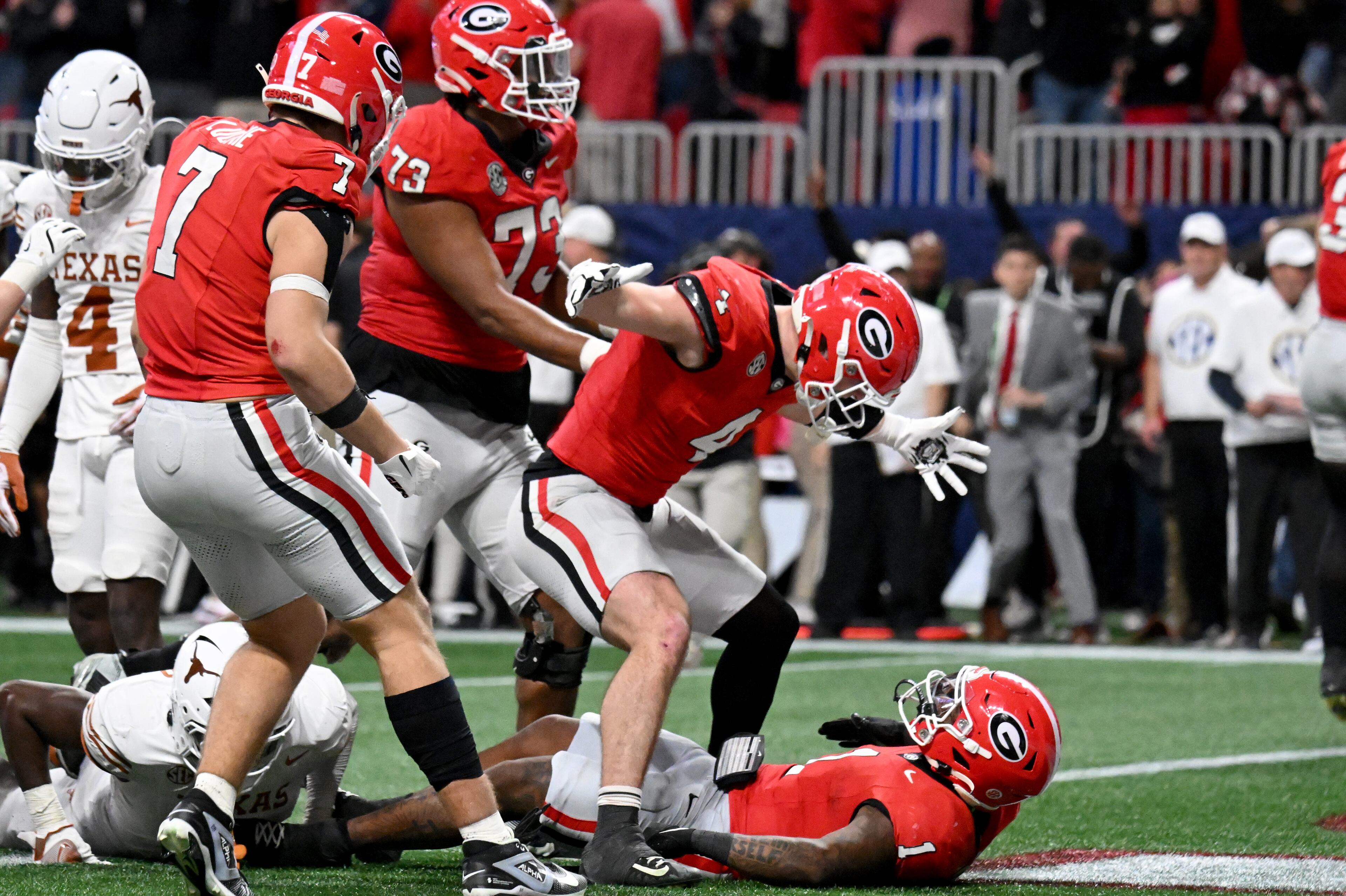 Georgia running back Trevor Etienne (1) is surrounded by teammates after scoring the game winning touchdown in overtime during the SEC Championship football game at the Mercedes-Benz Stadium, Saturday, December 7, 2024, in Atlanta. Georgia won 22-19 over Texas in overtime. (Hyosub Shin / AJC)