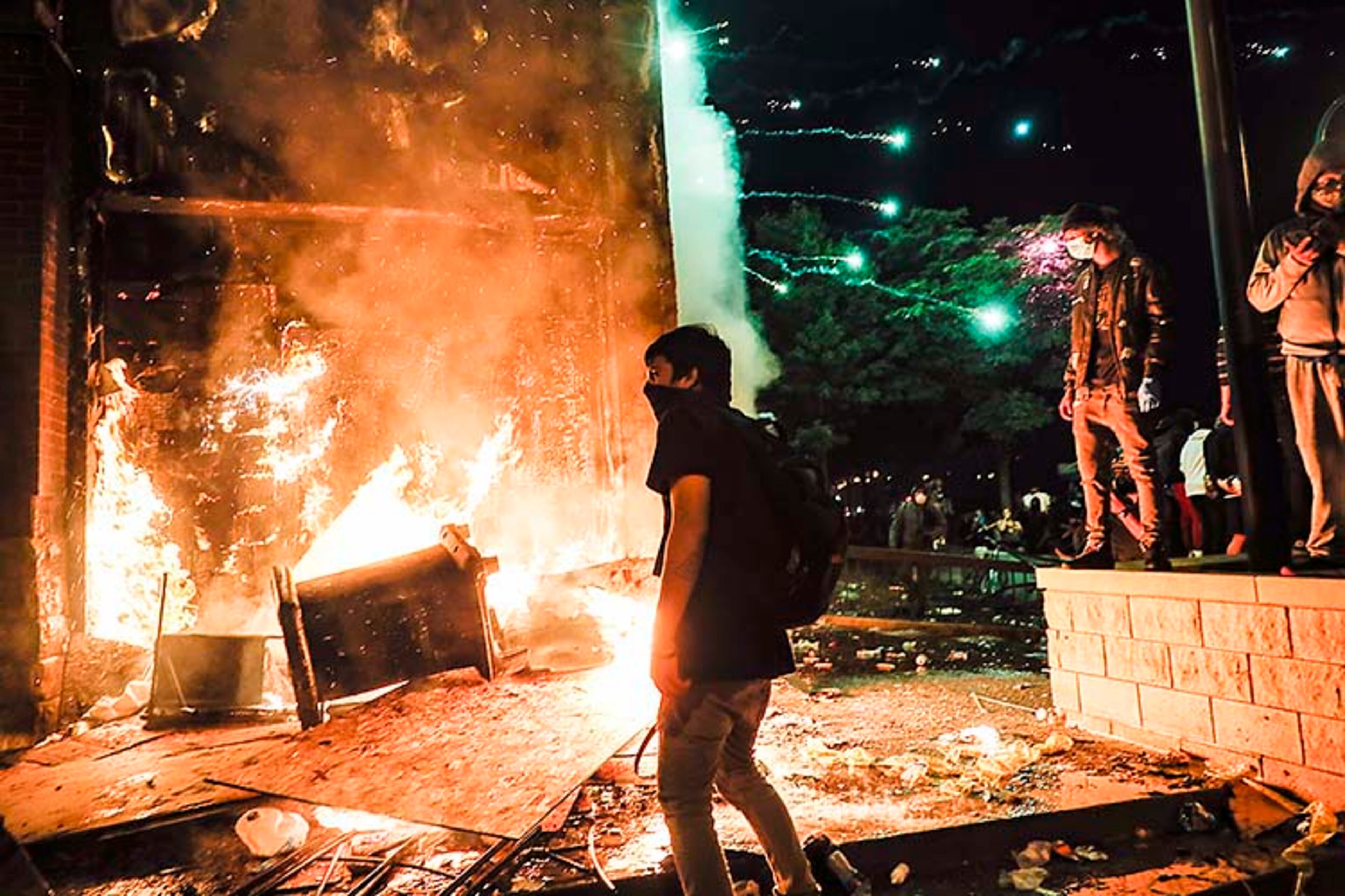 Protestors demonstrate outside of a burning Minneapolis 3rd Police Precinct, Thursday, May 28, 2020, in Minneapolis. Protests over the death of George Floyd, a black man who died in police custody Monday, broke out in Minneapolis for a third straight night. (AP Photo/John Minchillo)