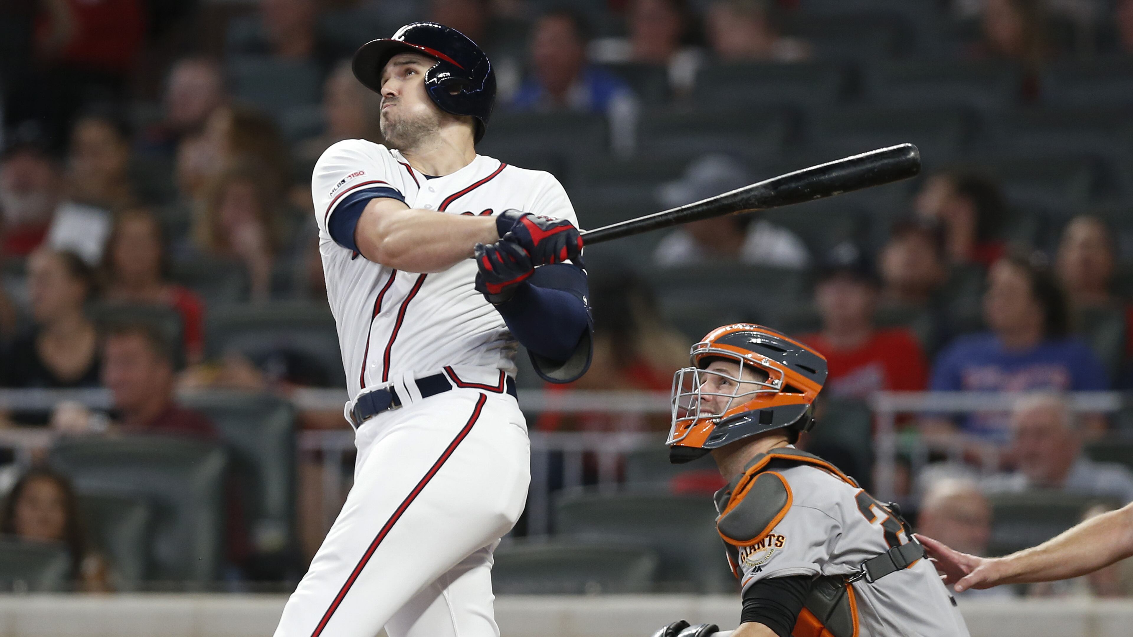The Braves’ Adam Duvall hits a two-run homer in the seventh inning while Giants catcher Buster Posey looks on during Saturday’s game at SunTrust Park.