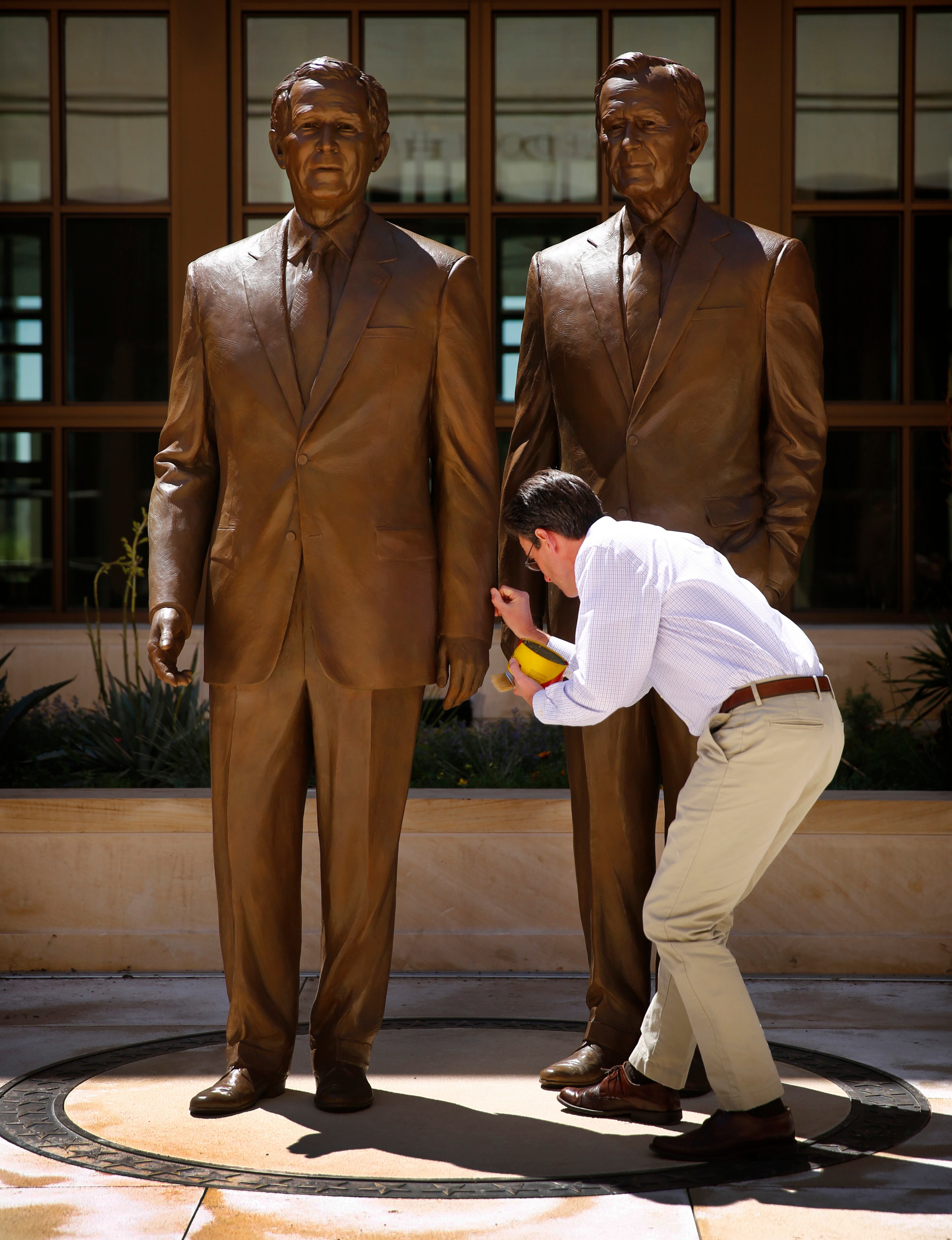 Sculptor Chas Fagan, of Charlotte, applies wax to the 8-ft bronze statues he created of former Presidents George W. Bush, left, and George H.W. Bush in the courtyard of the George W. Bush Presidential Center, April 19, 2013 in University Park, Texas. (Tom Fox/Dallas Morning News/MCT)