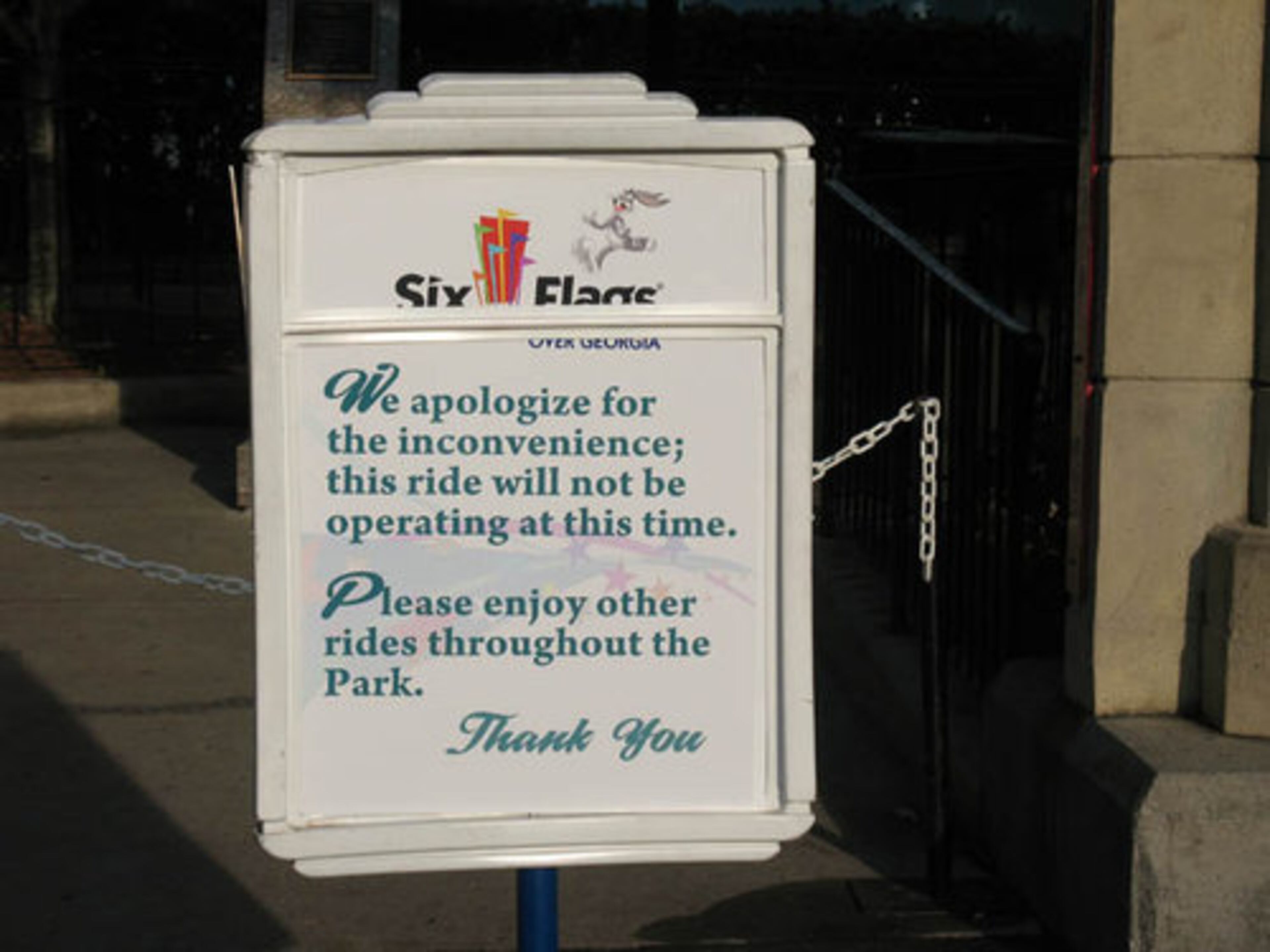 A sign in front of the roller coaster apologizes to patrons for the ride being closed.