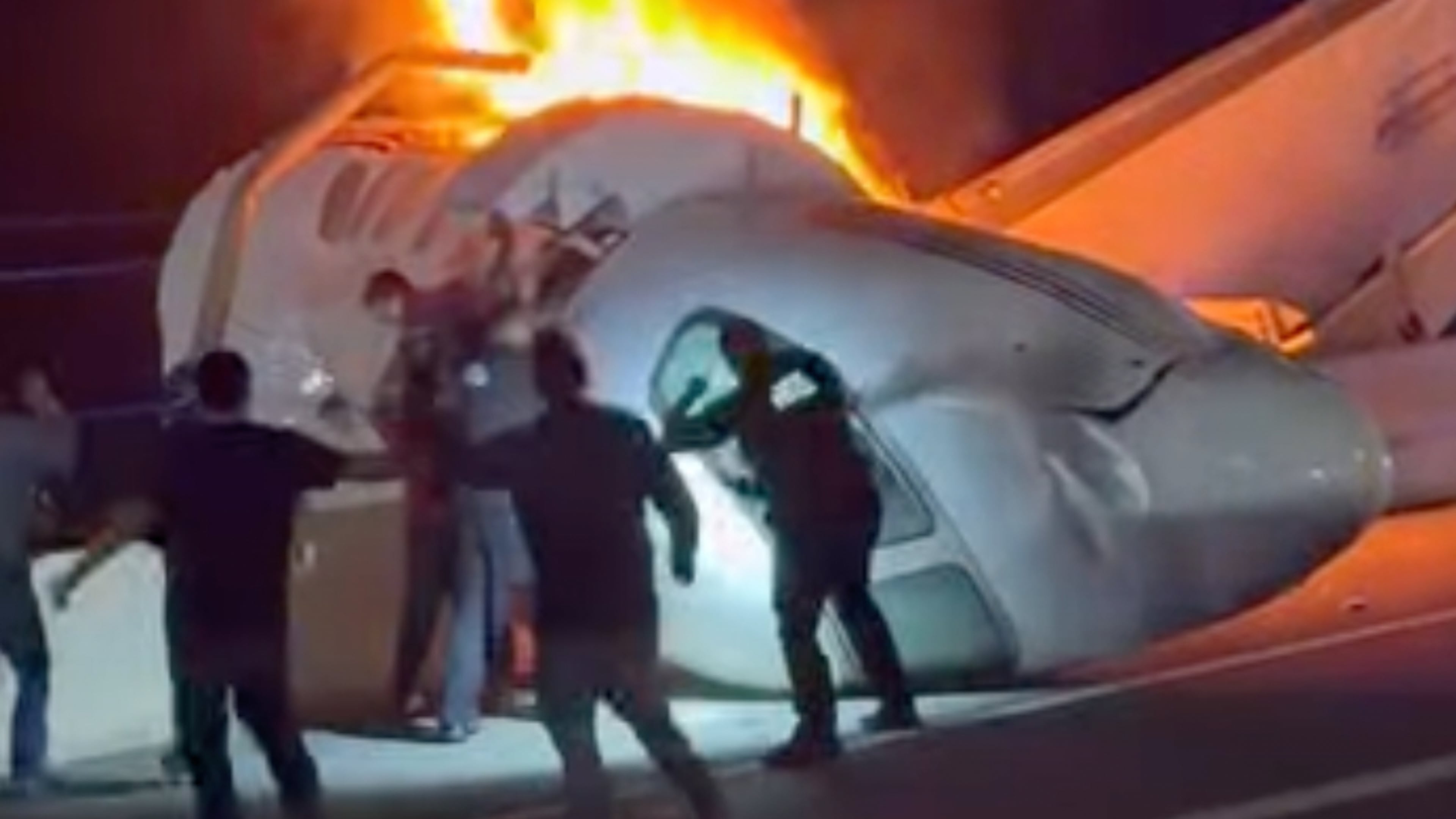 A passenger, top, jumps out of a plane after it crashed on a highway as other people help Tuesday, June 16, 2026, in Laredo, Texas. (Zayra Garza via AP)