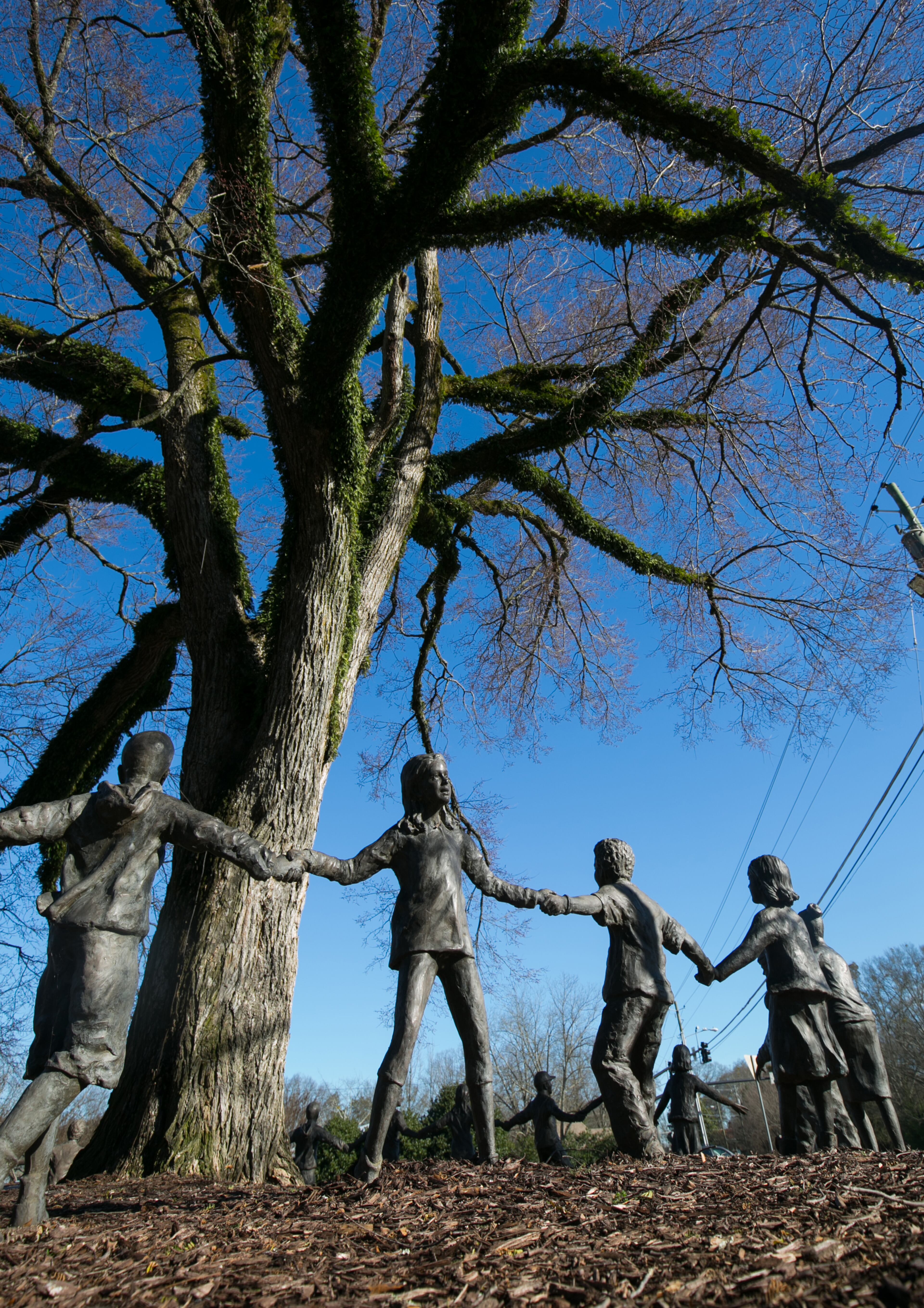 The sculpture, "Friendship Ring," is shown on the grounds of the Alpharetta Community Center Thursday, February 4, 2016, in Alpharetta, Ga. The piece is a circle of statues around the base of a gigantic elm tree. This story is about the backstory on three works of public art. PHOTO / JASON GETZ