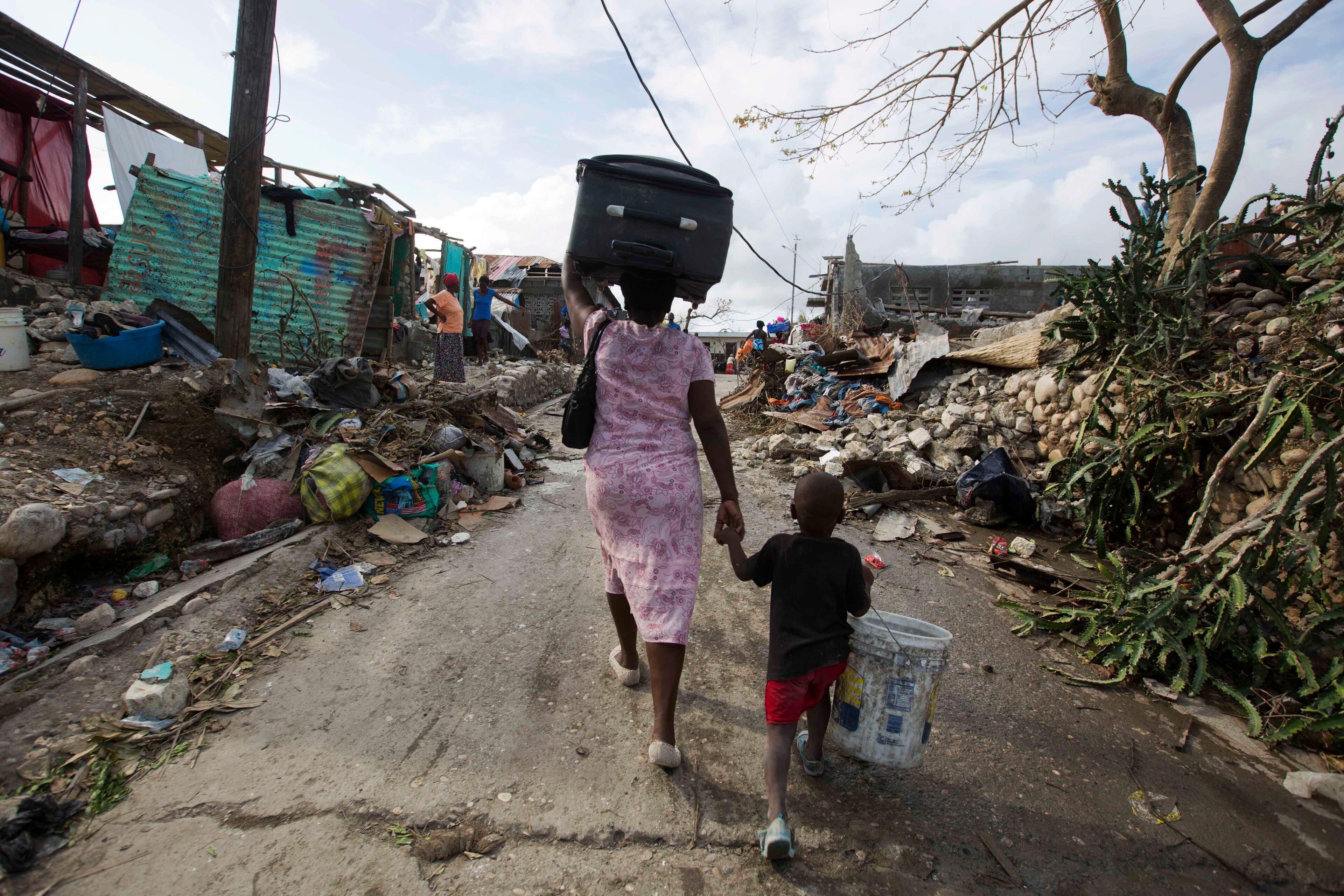 A woman walks to a shelter with her son as they leave after their home was destroyed by Hurricane Matthew in Jeremie, Haiti on Sunday, Oct. 9, 2016. Jeremie appears to be the epicenter of the country's growing humanitarian crisis in the wake of the storm. (AP Photo/Dieu Nalio Chery)