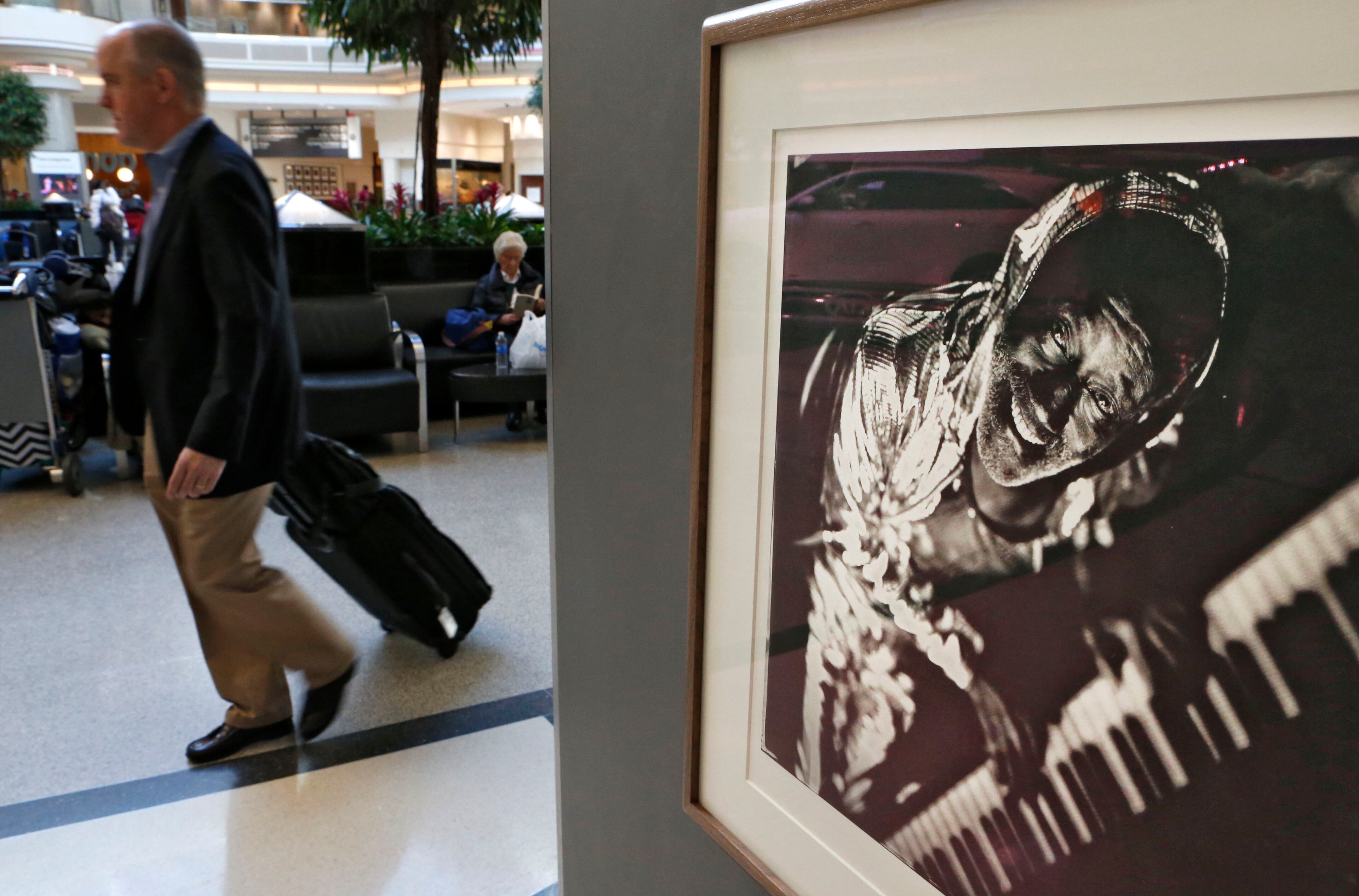Travelers pass this photograph titled "Ironing Board Sam, Entertainer, Hillsboro, NC." it is among the prints on display in the Hartsfield-Jackson airport atrium on Nov. 29, 2015. For 35 years photographer Tim Duffy has photographed Southern musicians and the world in which they live using wet-plate collodion photography.