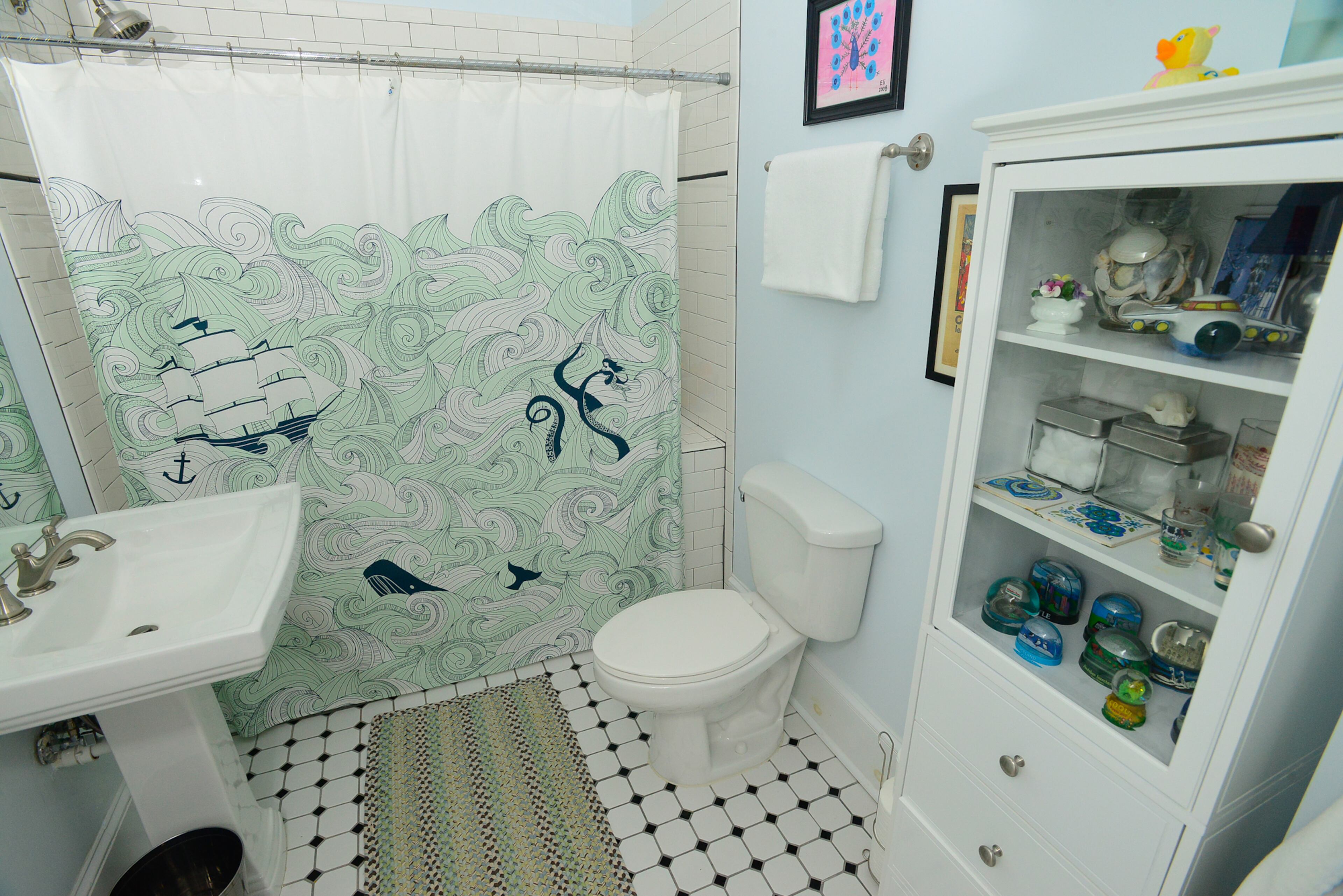 The walls of the guest bathroom are painted Benjamin Moore Mystical Blue, a theme that carries over to the nautical themed shower curtain.