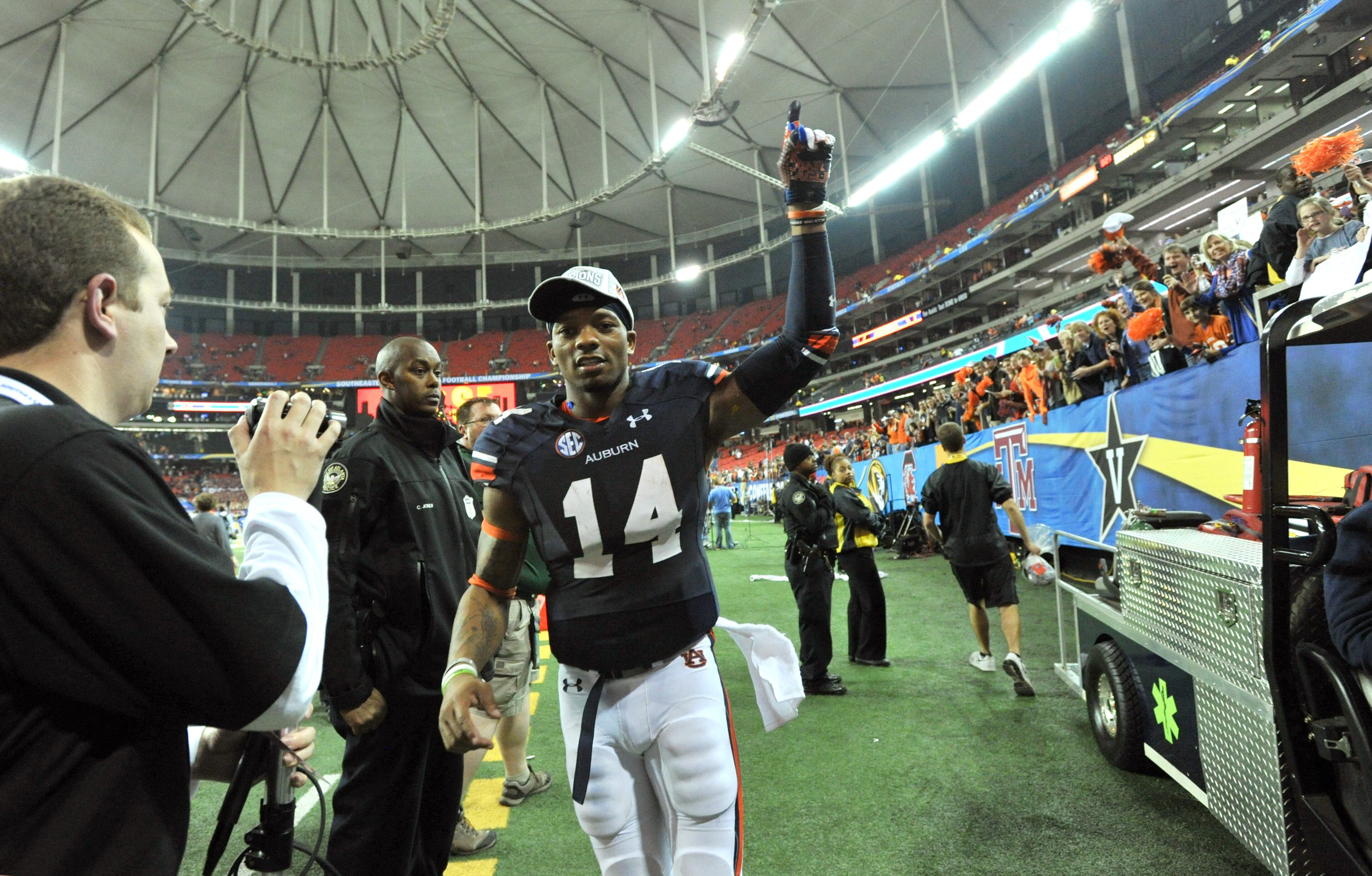 Auburn Tigers quarterback Nick Marshall (14) leaves the field as fans celebrate after Auburn won 59-42 during the SEC Championship game at Georgia Dome on Saturday, December 7, 2013. HYOSUB SHIN / HSHIN@AJC.COM