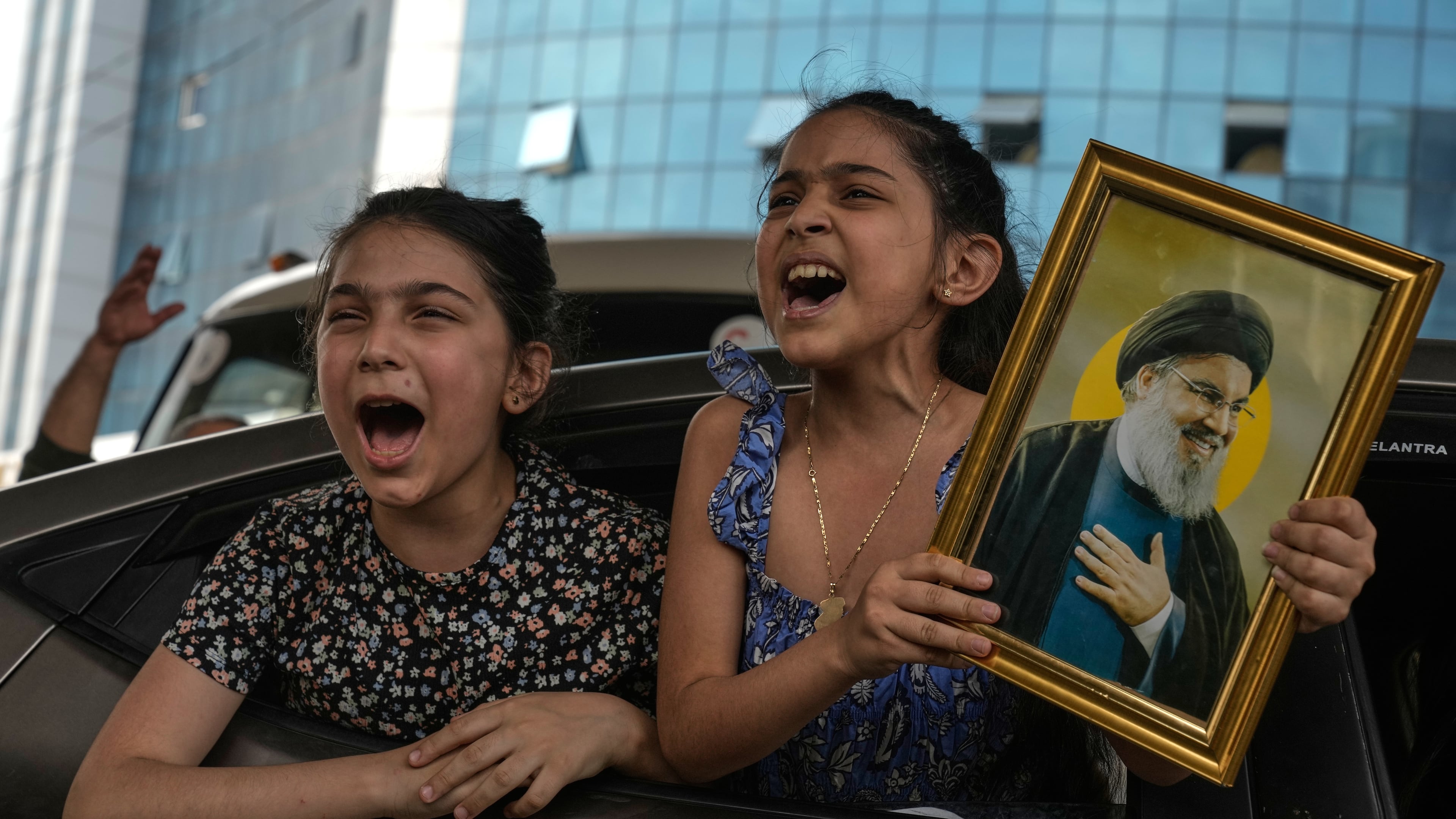 Two girls chant slogans as one holds an image of the late Hezbollah leader Hassan Nasrallah in Dahiyeh, Beirut's southern suburbs, Lebanon, Friday, April 17, 2026, following a ceasefire between Israel and Hezbollah. (AP Photo/Bilal Hussein)