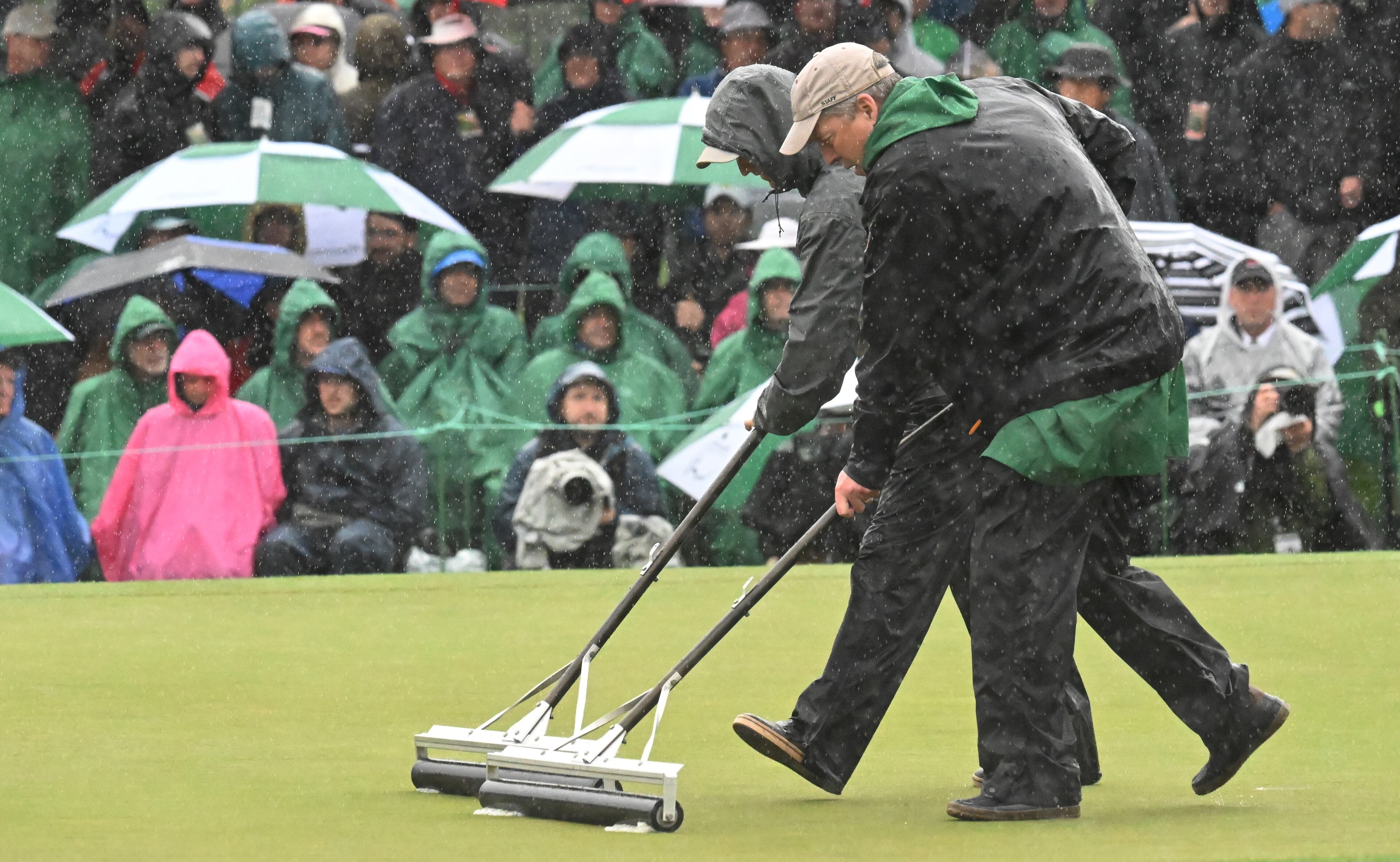 Crew clears water from 18th green during second round of the 2023 Masters Tournament at Augusta National Golf Club, Saturday, April 8, 2023, in Augusta, Ga. (Hyosub Shin / Hyosub.Shin@ajc.com)