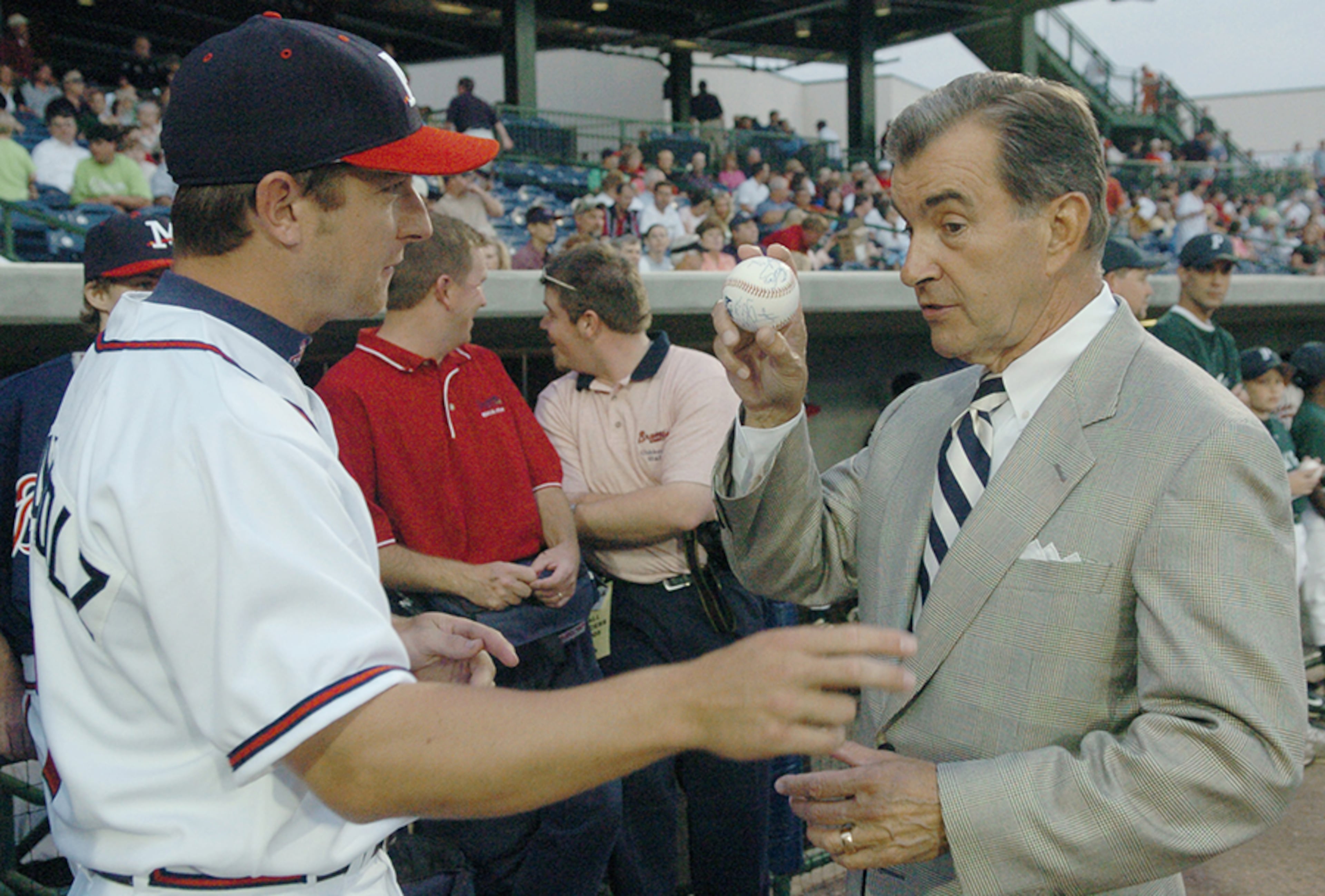 Atlanta Braves general manager John Schuerholz (right) jokes with his son, Mississippi Braves infielder Jon Schuerholz about "smoke" in the elder's ceremonial first pitch Monday, April 18, 2005, in Pearl, Miss., during the home opener of the newest Atlanta Braves affiliated Class Double-A baseball club.