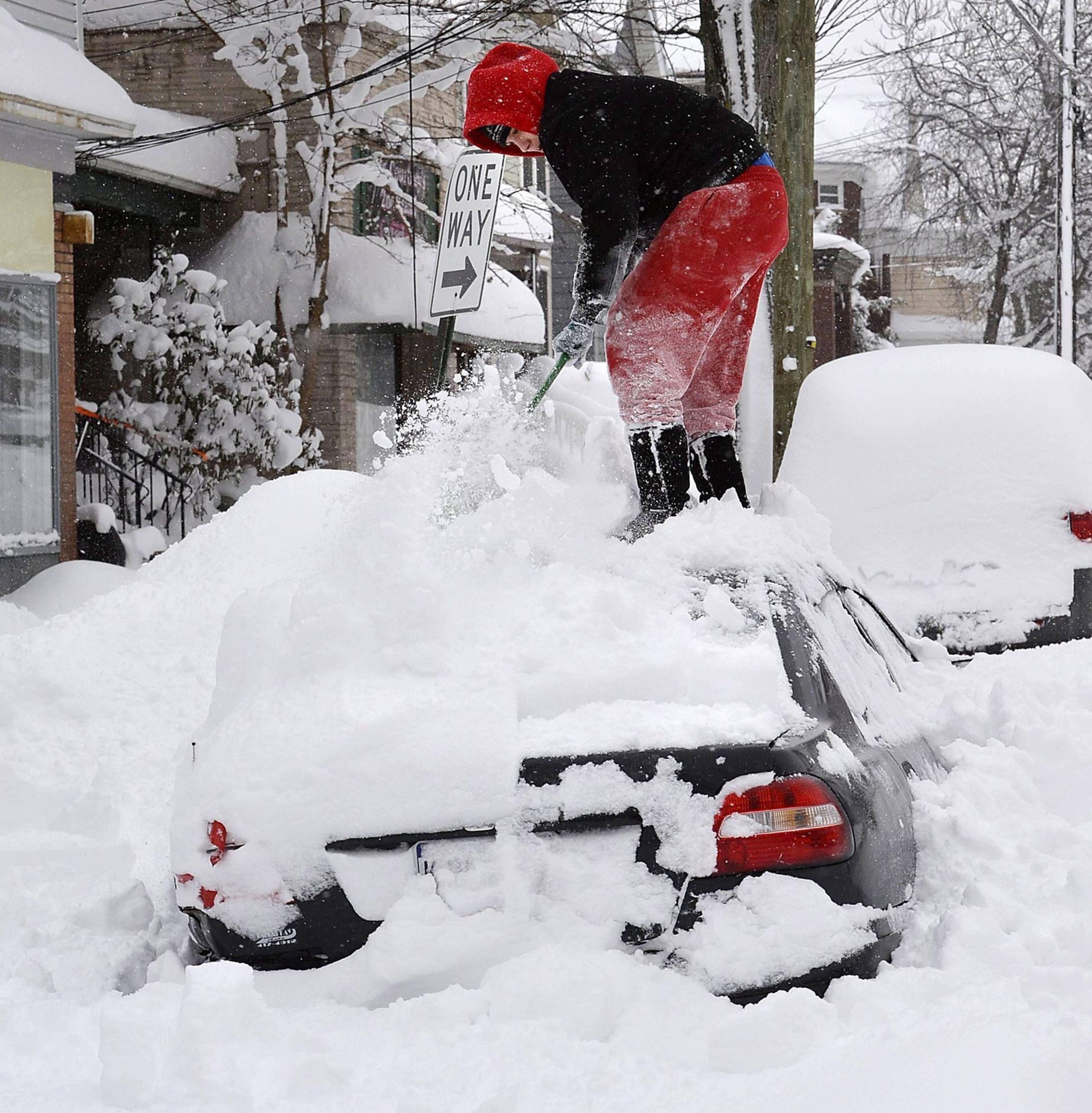 Soledda Hernandez stands on the roof of her car as she brushes off snow in Erie, Pa., Wednesday, Dec. 27, 2017. Snow continues to fall in Erie and surrounding areas that already have seen a record amount of snow over the past few days, prompting a disaster emergency declaration.
