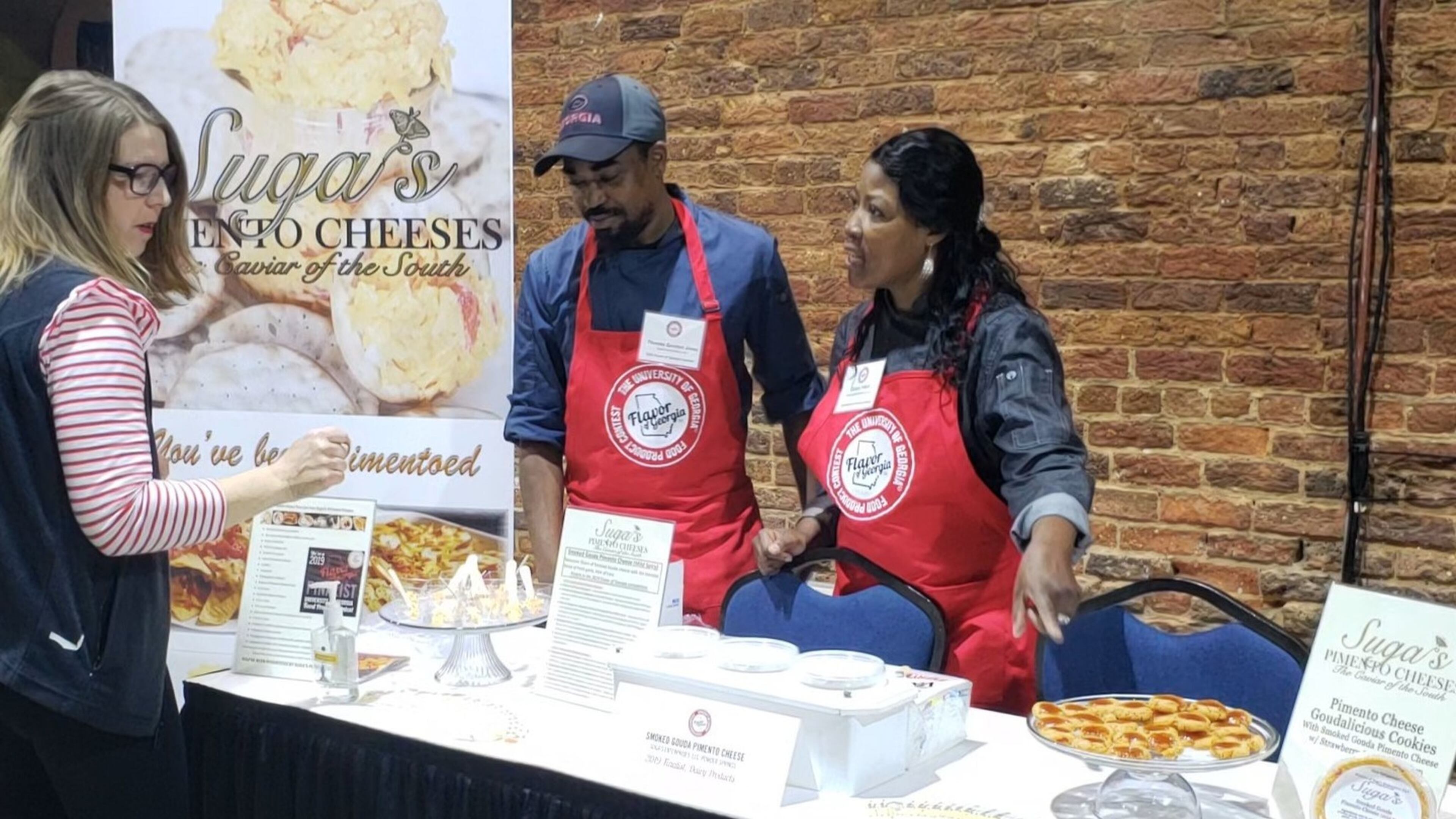 Stacey West (from right) and her son, Quinton Jones of Suga’s Pimento Cheese, talk with a visitor at the reception for finalists in the 2019 Flavor of Georgia competition. CONTRIBUTED BY ROBERT WEST