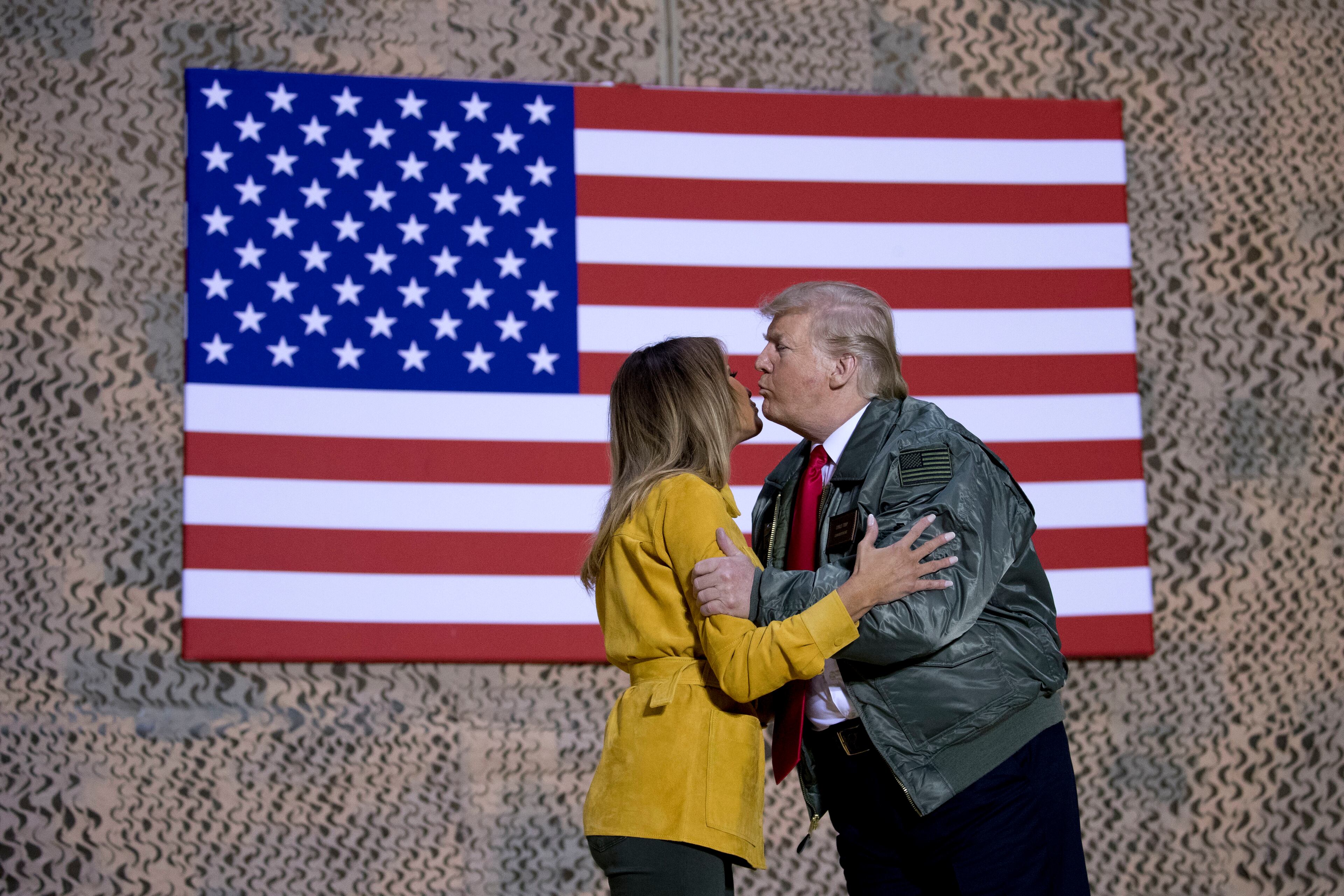 President Donald Trump kisses first lady Melania Trump during a hanger rally at Al Asad Air Base, Iraq, Wednesday, Dec. 26, 2018. President Donald Trump, who is visiting Iraq, says he has 'no plans at all' to remove US troops from the country. (AP Photo/Andrew Harnik)