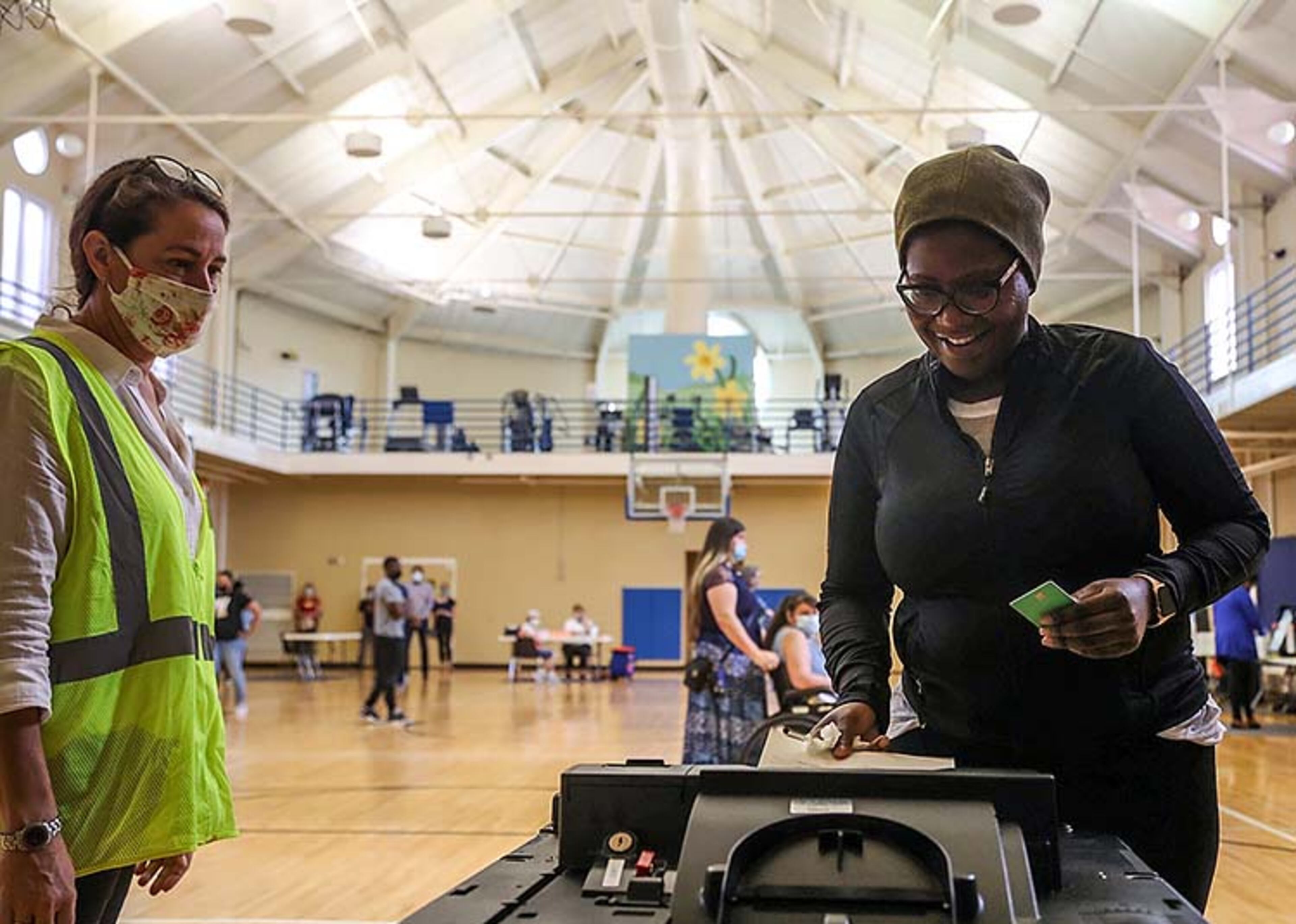 Cobb County Poll Clerk Andrea Keener (left) assists Smyrna resident Qris Dorvil as she places her ballot in the electronic ballot machine at the Smyrna Community Center.