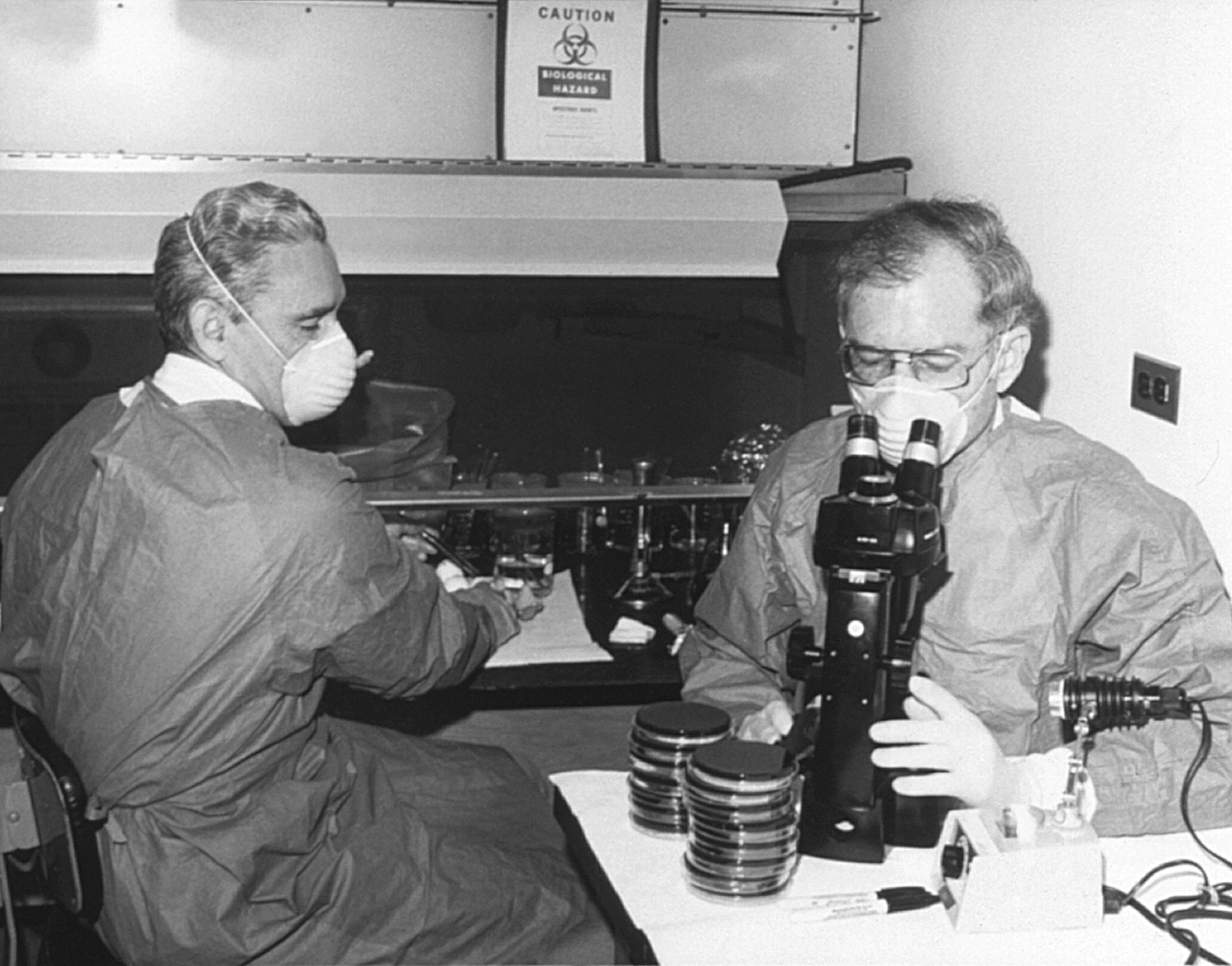 This 1978 photo shows Centers for Disease Control laboratorian George Gorman (left) along with Dr. Jim Feeley while they were examining culture plates, i.e., Petri dishes, upon which the first environmental isolates of Legionella pneumophils had been grown. -- Text by the CDC