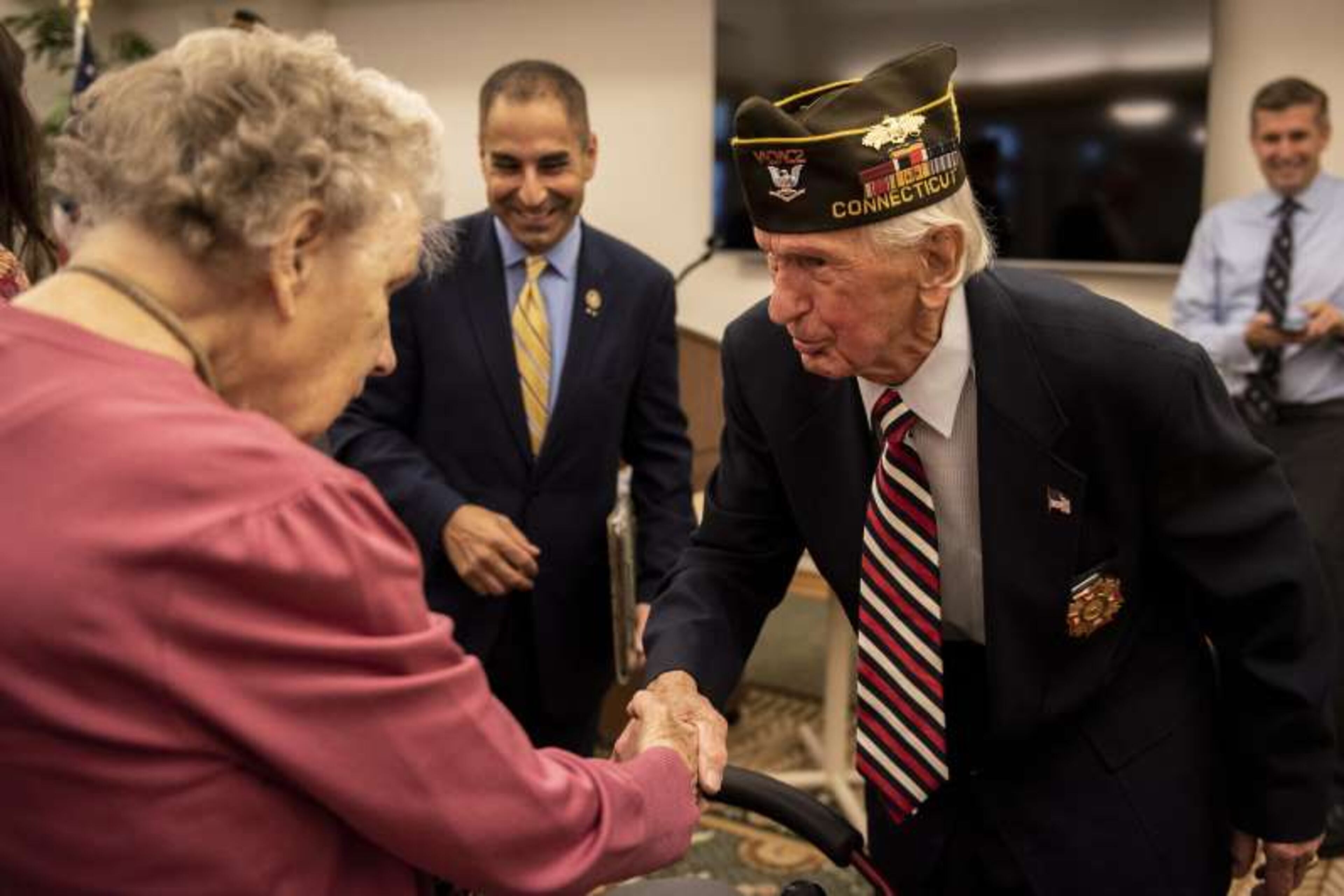 Ben Walker, 93, shakes hands with Alice Johnson, 95, while state Department of Veterans' Affairs Thomas Saad looks on.