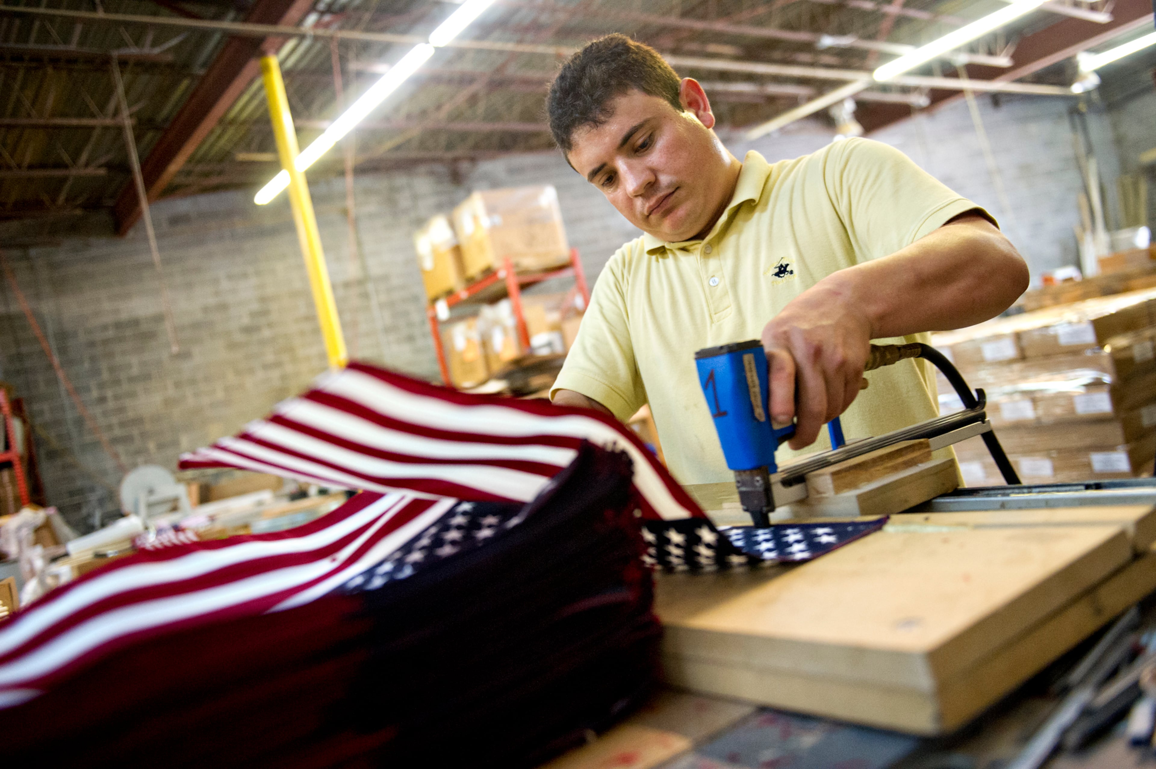 Rosendo Flores staples an American flag onto a stake at U.S. Flag Makers in Marietta on Wednesday, July 2, 2014. JONATHAN PHILLIPS / SPECIAL
