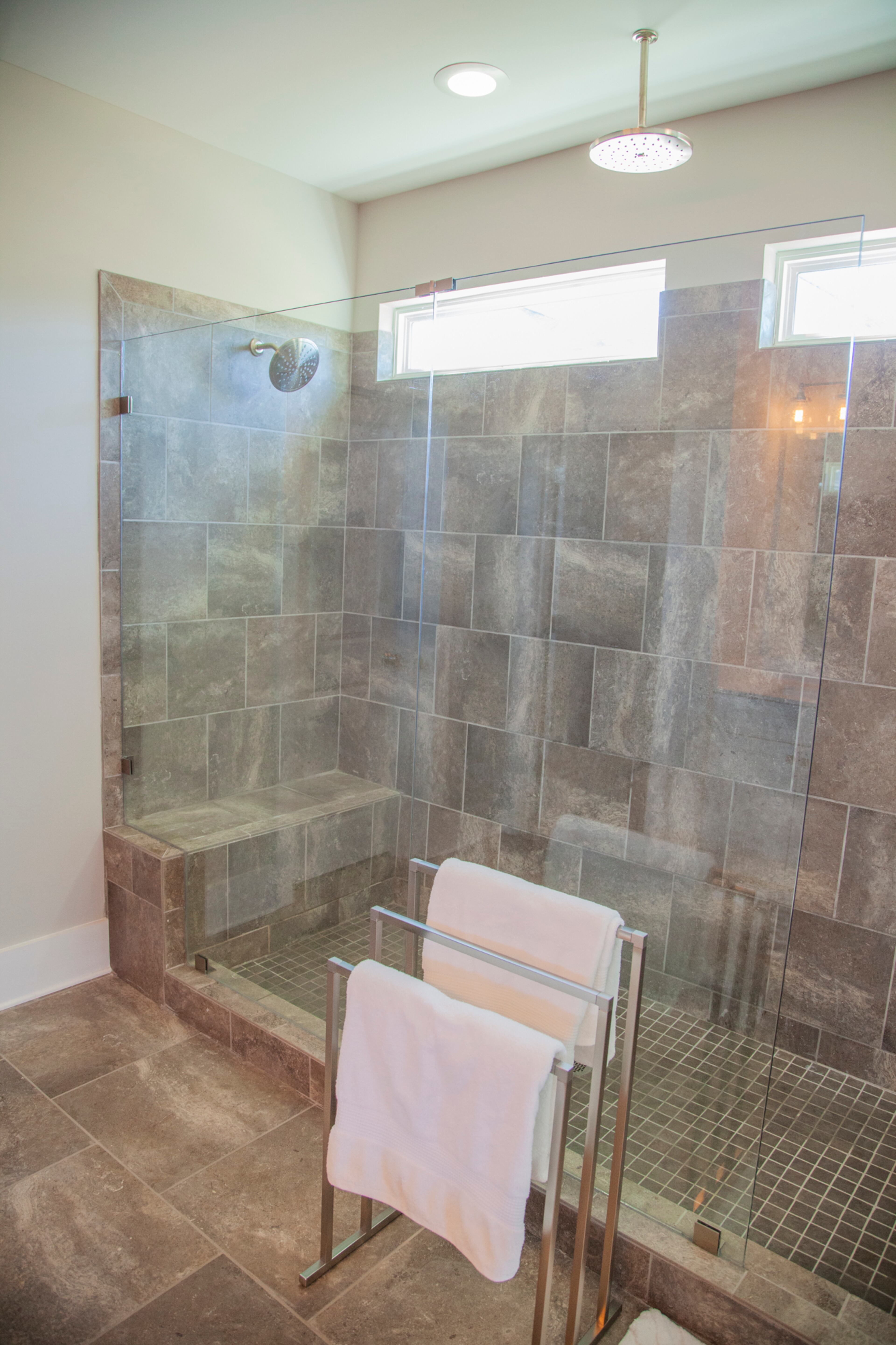 An oversized frameless glass shower in the master bathroom features two rainfall shower heads at different heights and angles. The high windows let in natural light. Text by Kat Khoury/Fast Copy News Service. Photo by Reann Huber.