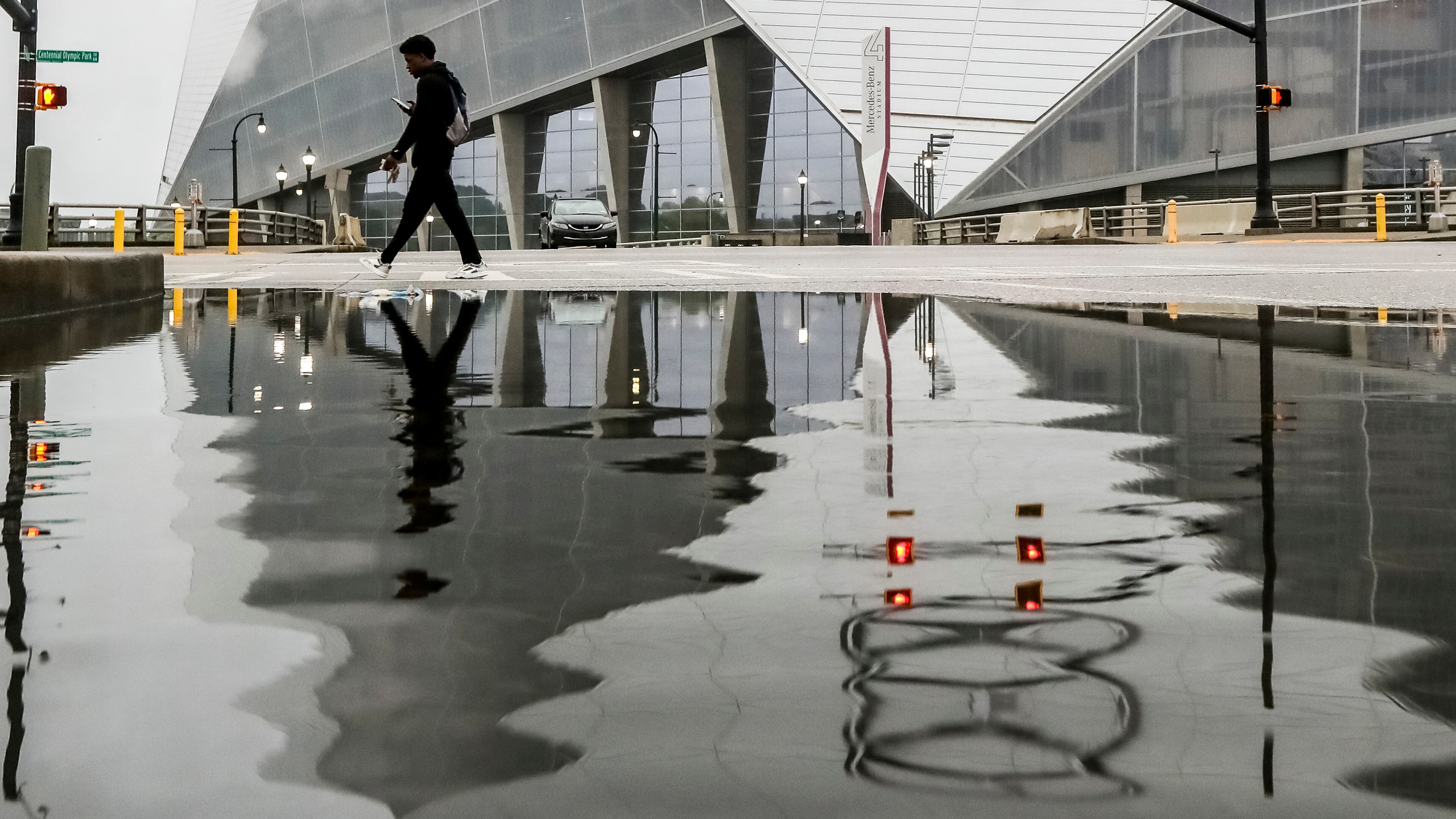 Quarnadius Wood steers clear of a puddle at the intersection of Martin Luther King Jr. Drive and Centennial Olympic Park Drive, where Taylor Swift fans flocked to Friday night for the first of the pop icon's three sold-out shows at Mercedes-Benz Stadium.