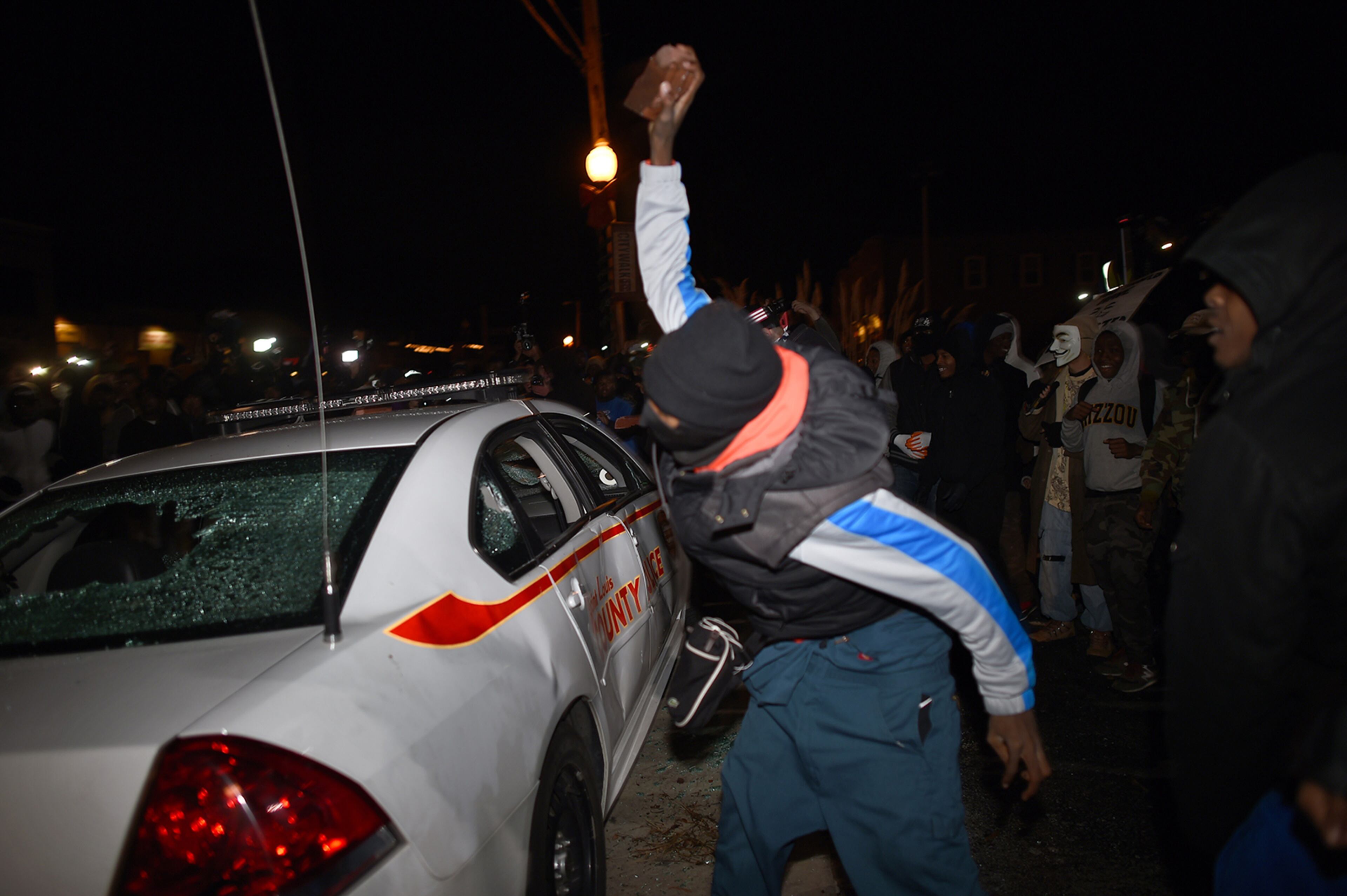 A demonstrator attacks a police car after learning that the police officer who shot dead 18-year-old Michael Brown will not face charges, outside the police station in Ferguson, Missouri, on November 24, 2014. US President Barack Obama urged calm on November 24 as violent protests broke out on the streets of Ferguson after a grand jury decided a white policeman will not face charges for killing a black teen. AFP PHOTO/Jewel Samad (Photo credit should read JEWEL SAMAD/AFP/Getty Images)