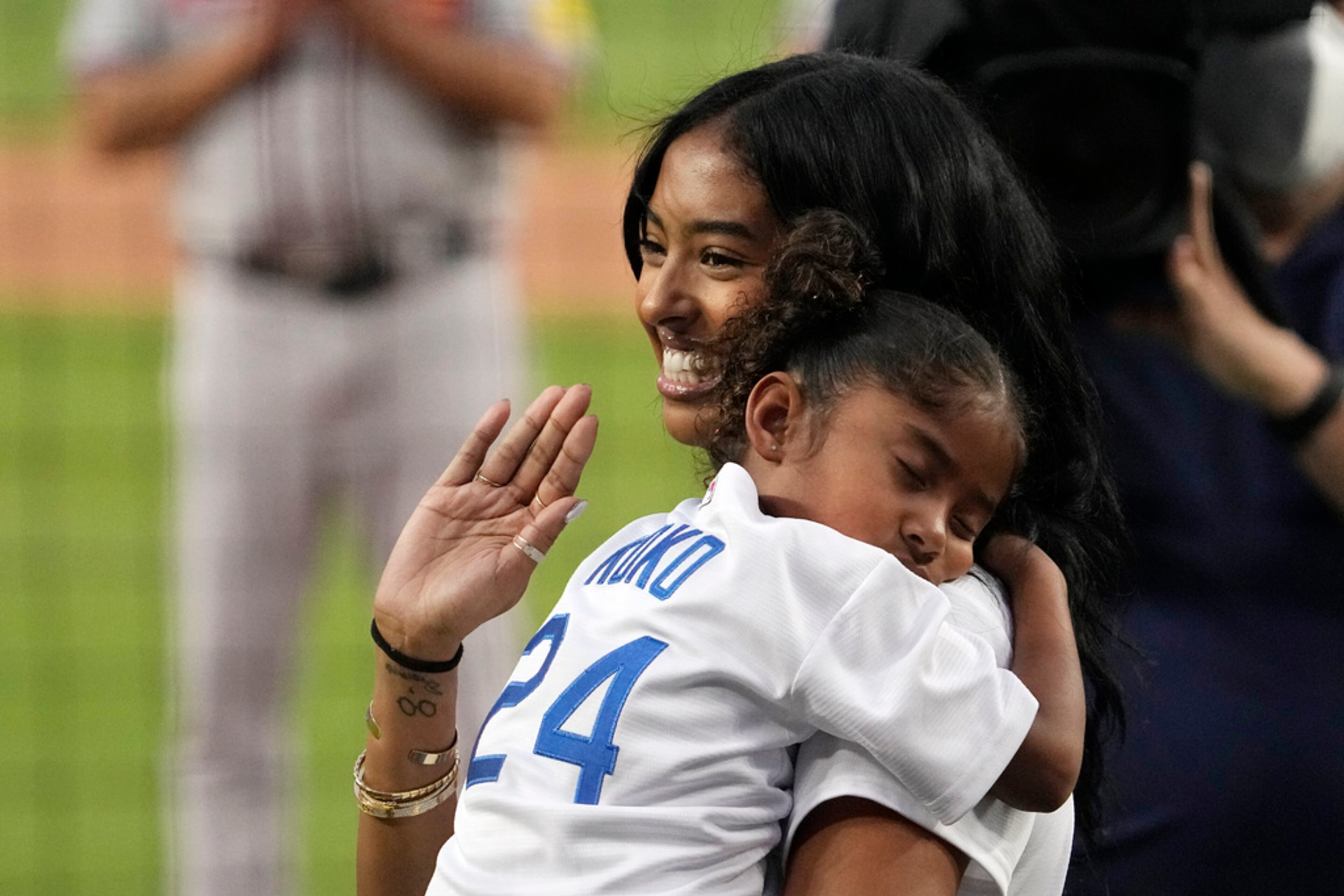 Natalia Bryant, daughter of Kobe Bryant, holds her sister Capri Bryant before throwing out the ceremonial first pitch prior to a baseball game between the Los Angeles Dodgers and the Atlanta Braves Friday, Sept. 1, 2023, in Los Angeles. (AP Photo/Mark J. Terrill)