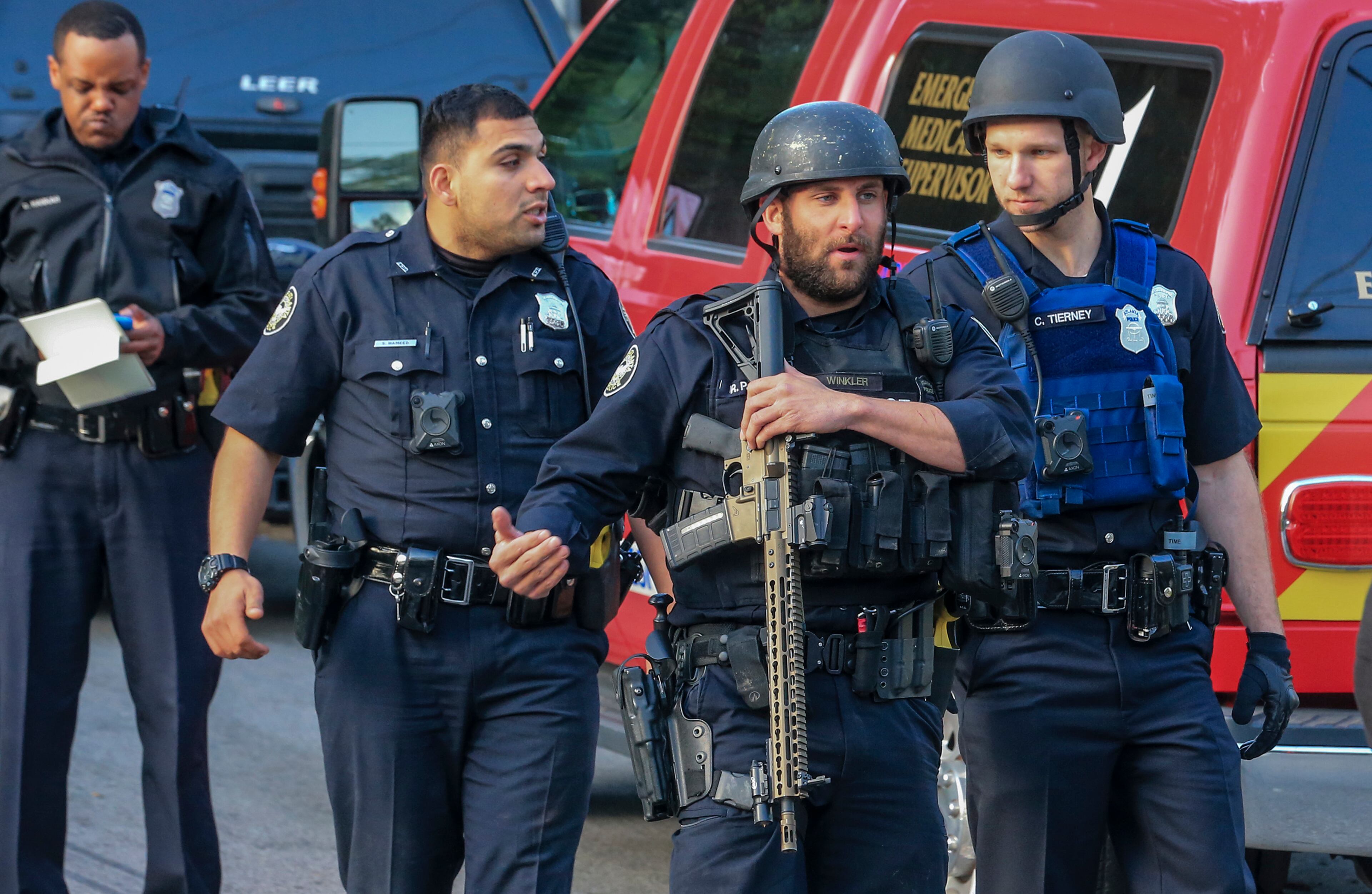 Atlanta police uniform officers bring an officer to medics to treat minor cuts after he injured himself to avoid gunfire before a six hour standoff began with the suspect being fatally shot Thursday morning, April 12, 2018 in northwest Atlanta. SWAT officers swarmed the 1400 block of Kennesaw Drive. (JOHN SPINK/JSPINK@AJC.COM)