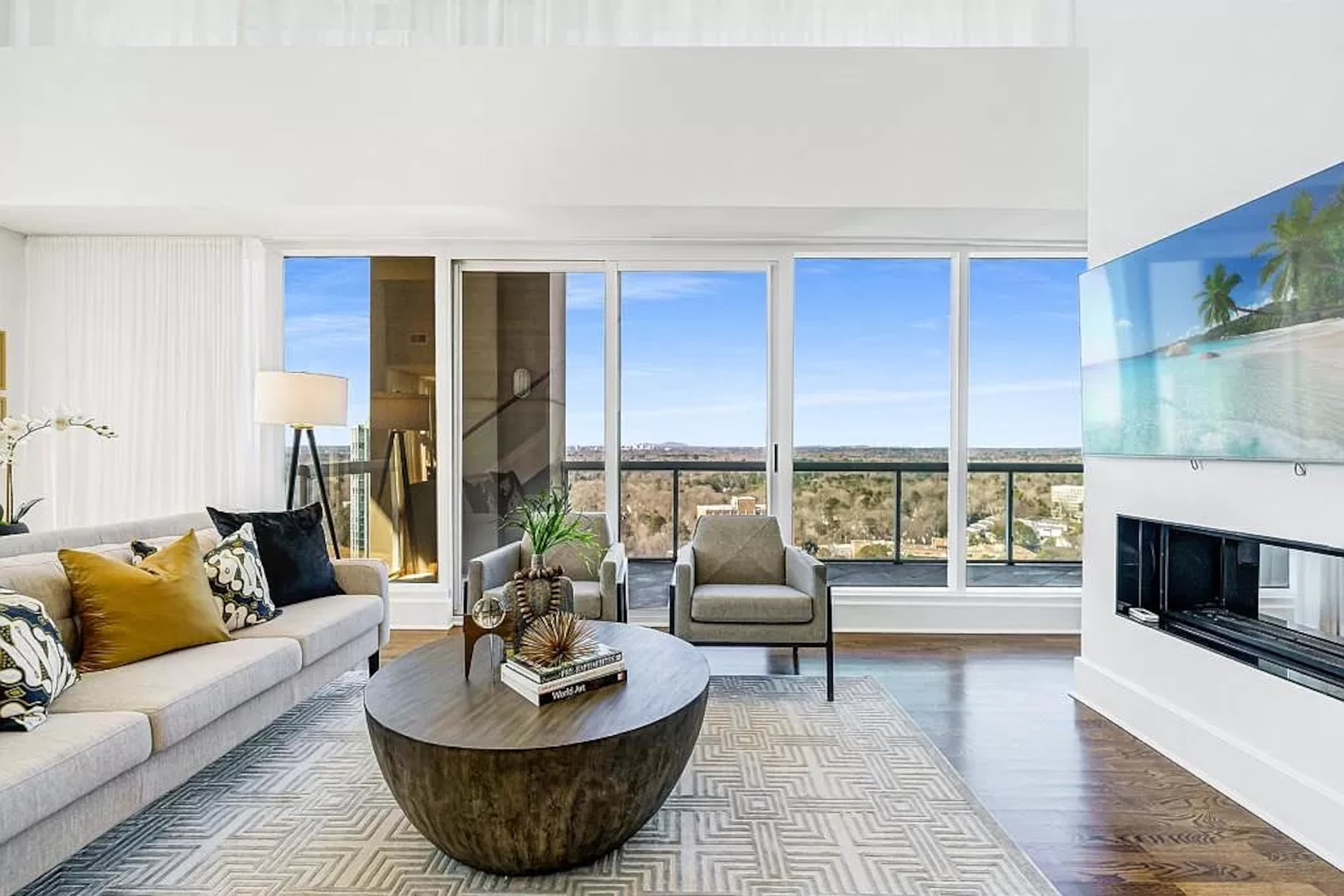 Offering two-story floor-to-ceiling windows with corner views, the sun-drenched main living area impresses with a double-sided fireplace dividing two spaces without interrupting the flow.