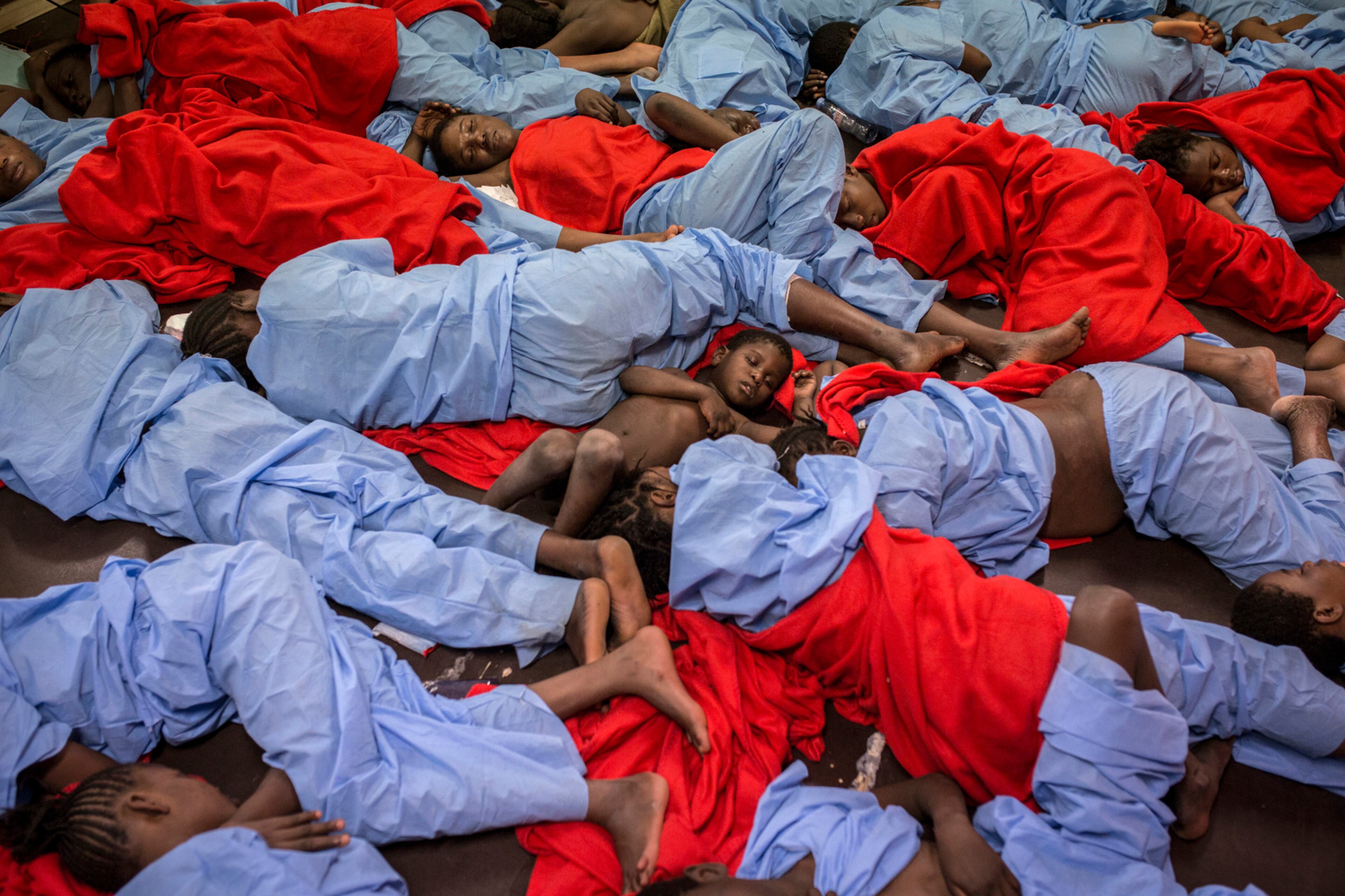 In this Friday Jan. 13, 2017 photo, Idris 3, from Mali, center, sleeps next to his mother Aicha Keita, right, on the deck of the Golfo Azzurro vessel after being rescued from the Mediterranean sea, about 20 miles north of Ra's Tajura, Libya. Spain's maritime rescue service says the bodies of seven African migrants have been found dead along the Strait of Gibraltar since Friday. (AP Photo/Olmo Calvo)