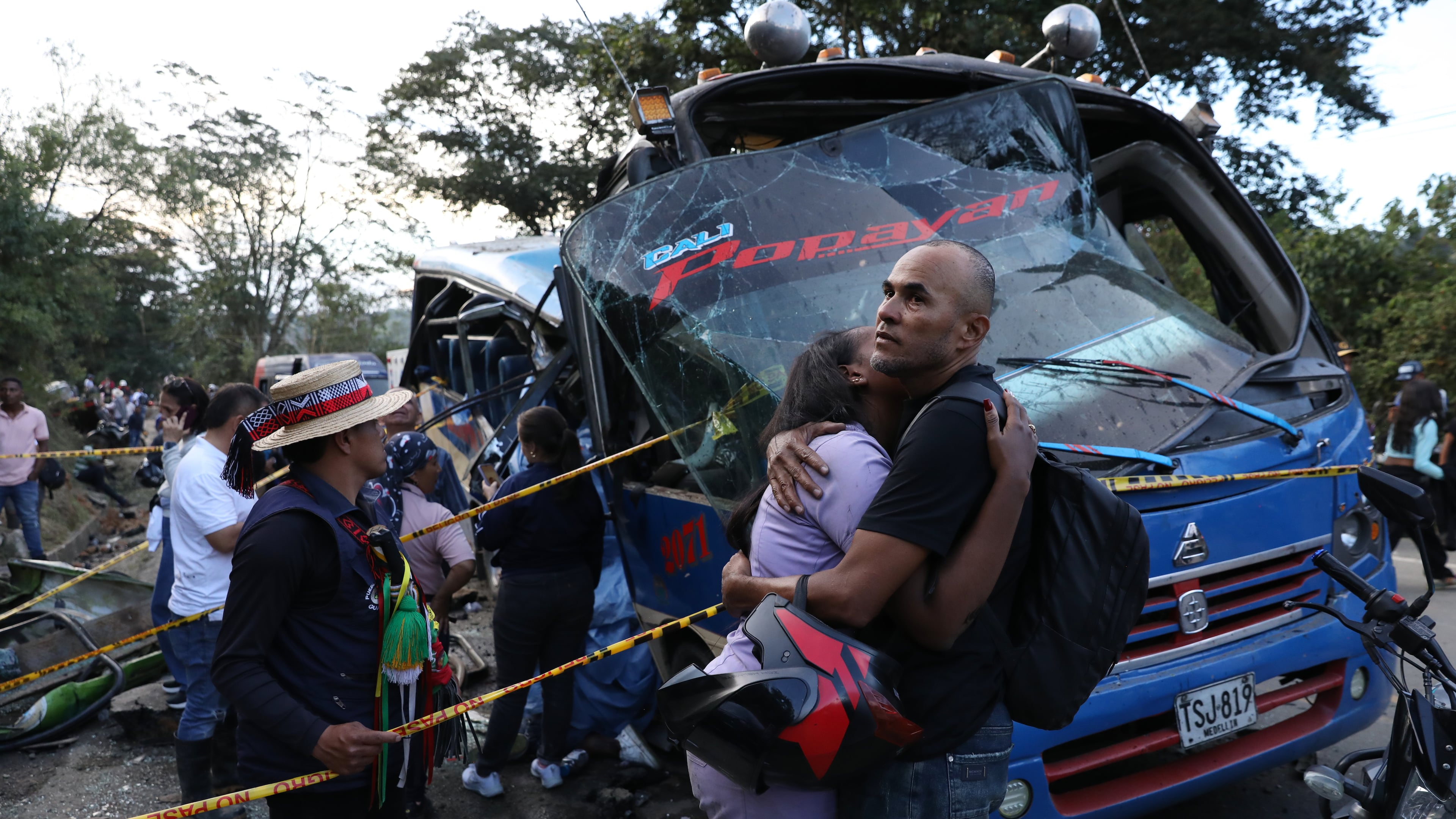 Relatives of victims embrace in front of a bus hit by an explosive device on the Pan-American Highway in Cajibio, Colombia, Saturday, April 25, 2026, after an attack blamed by authorities on dissident groups of the former FARC rebels killed at least a dozen people. (AP Photo/Santiago Saldarriaga)