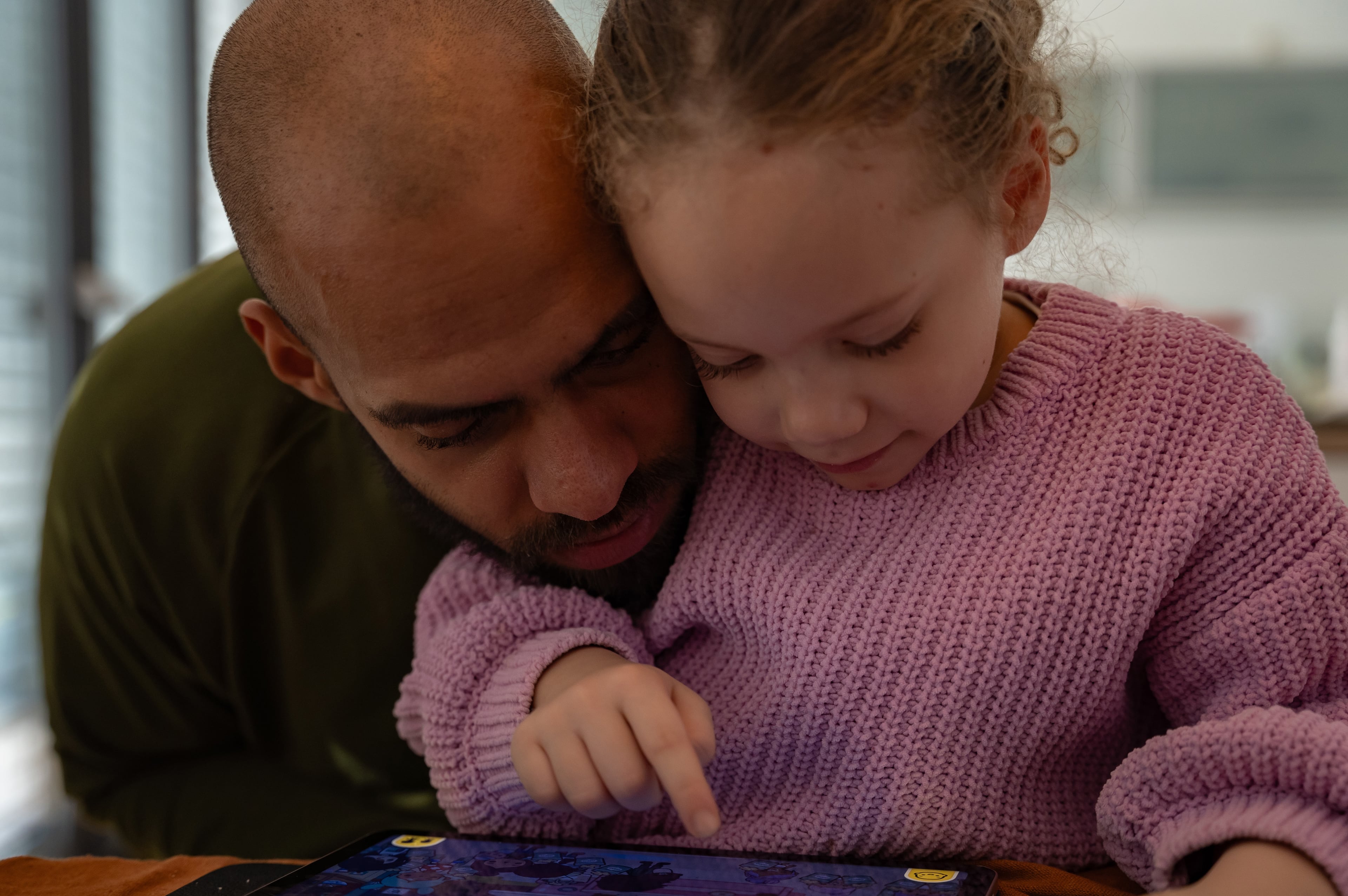 Kasim Edebali, who played six seasons as a linebacker in the NFL, and his daughter Yara play a game on a tablet, in Hamburg, Germany, Oct. 25, 2023. (Patrick Junker/The New York Times)