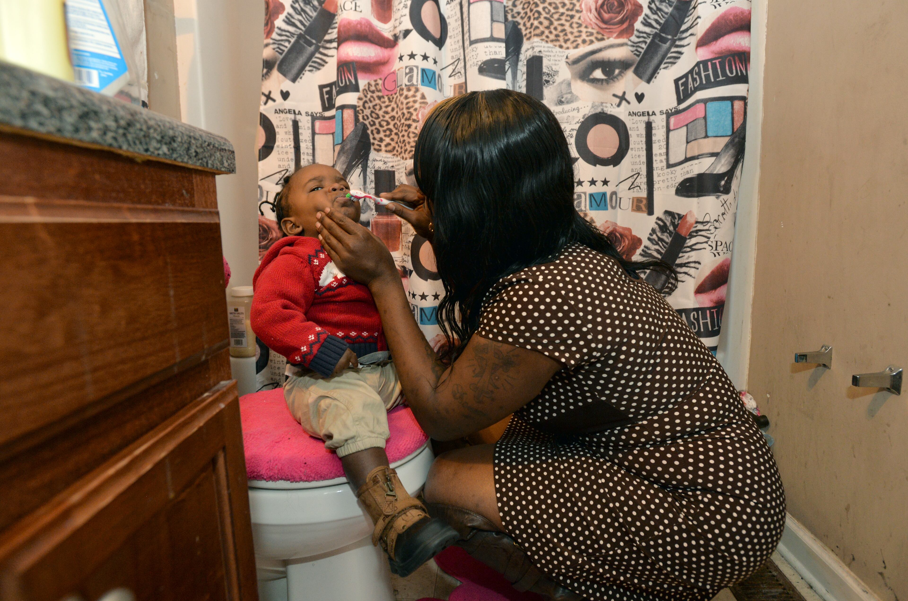 Ashley Roberson, 23, brushes her 1-year-old son Demetrius Broadnax Jr.'s teeth as she and her family get ready to go to church. HYOSUB SHIN / HSHIN@AJC.COM
