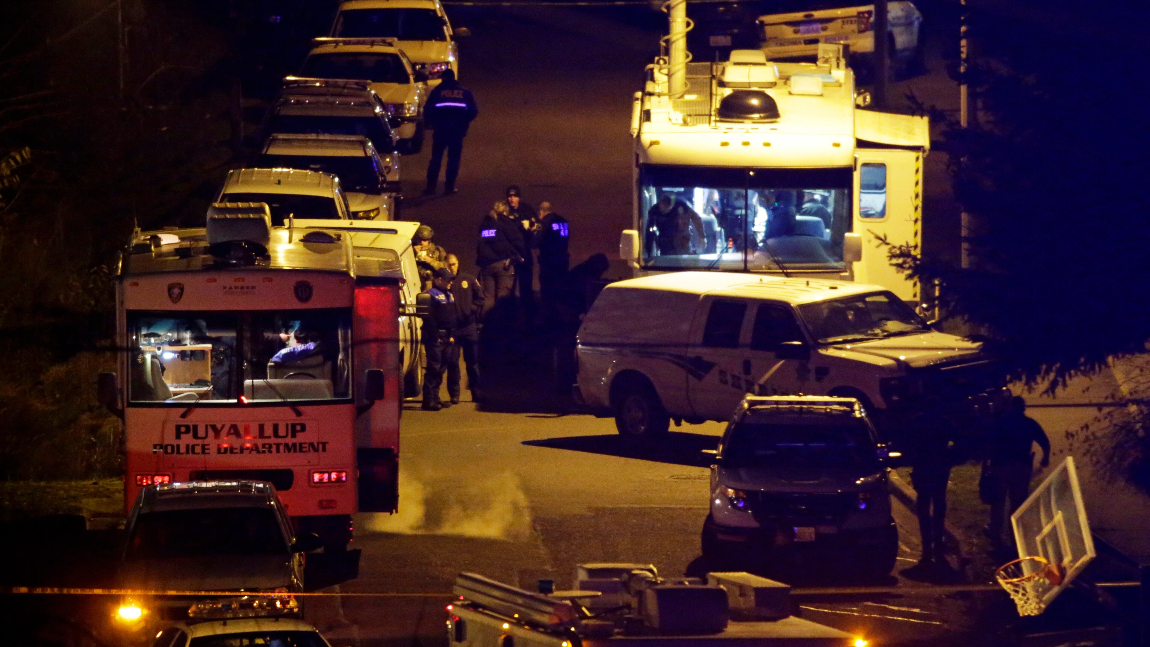 Law enforcement officers stand by command vehicles on East 52nd Street in Tacoma, Wash., in the early hours of Thursday, Dec. 1, 2016, near the home where a Tacoma Police officer was fatally shot Wednesday. The police officer who was shot multiple times while responding to a domestic violence call died Wednesday night, while police worked to arrest a suspect they believed was still barricaded in the home with a gun, authorities said. (AP Photo/Ted S. Warren)
