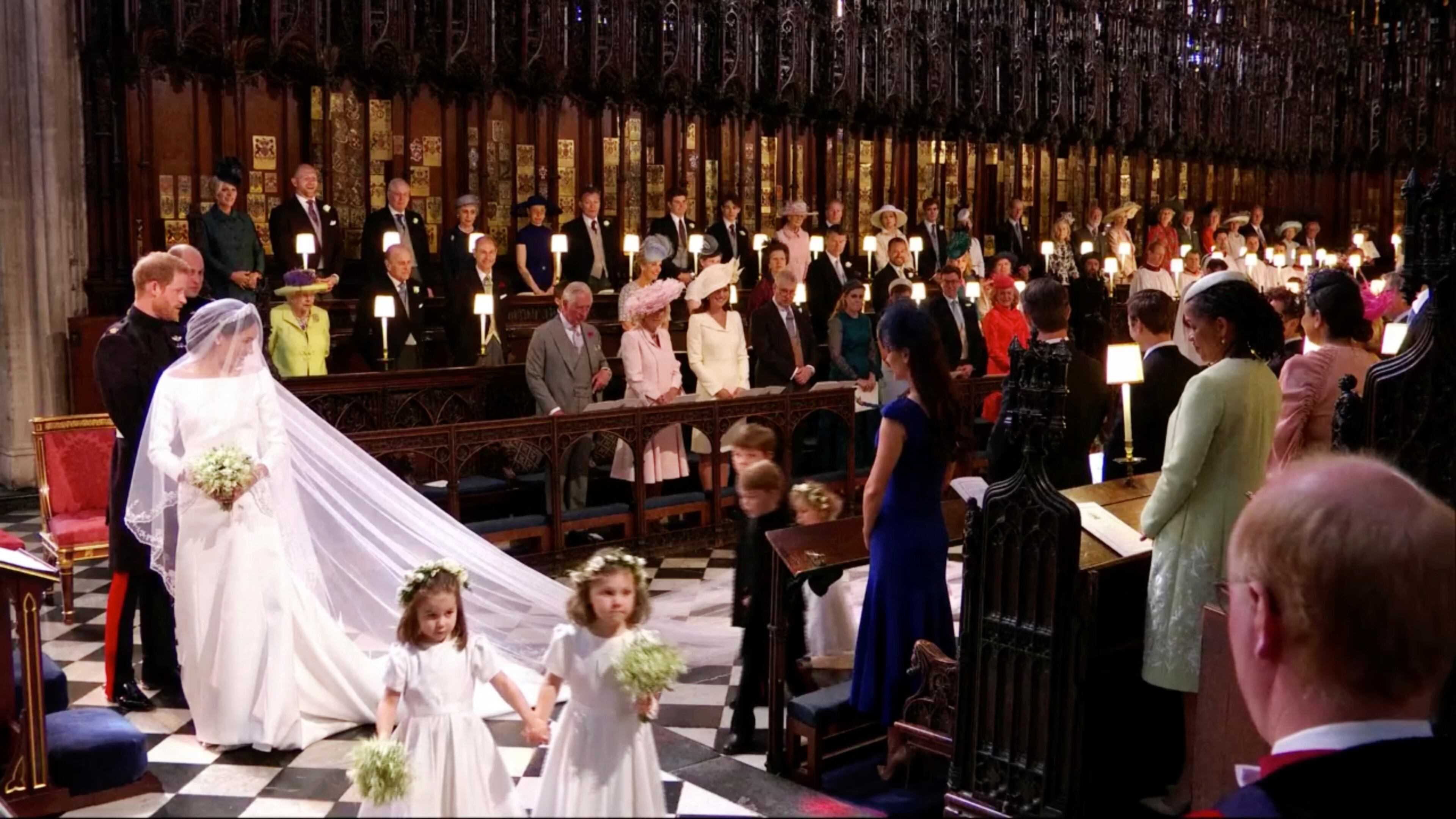In this frame from video, Britain's Prince Harry and Meghan Markle watch as the bridesmaids and page boys walk down the aisle at their wedding ceremony at St. George's Chapel in Windsor Castle in Windsor, near London, England, Saturday, May 19, 2018. (UK Pool/Sky News via AP)