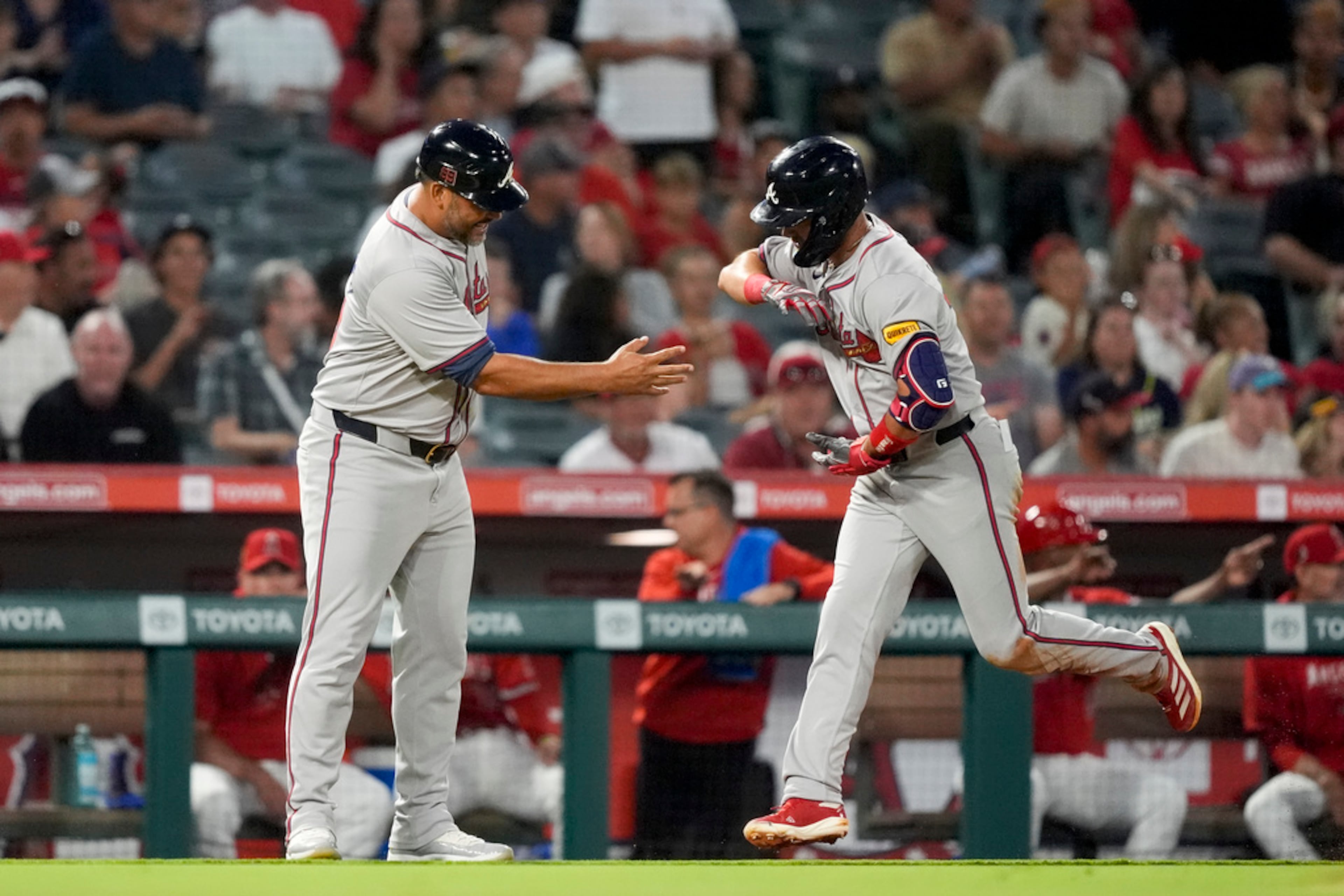 Atlanta Braves' Whit Merrifield, right, celebrates with third base coach Matt Tuiasosopo, left, after hitting a solo home run during the fifth inning of a baseball game against the Los Angeles Angels, Saturday, Aug. 17, 2024, in Anaheim, Calif. (AP Photo/Ryan Sun)