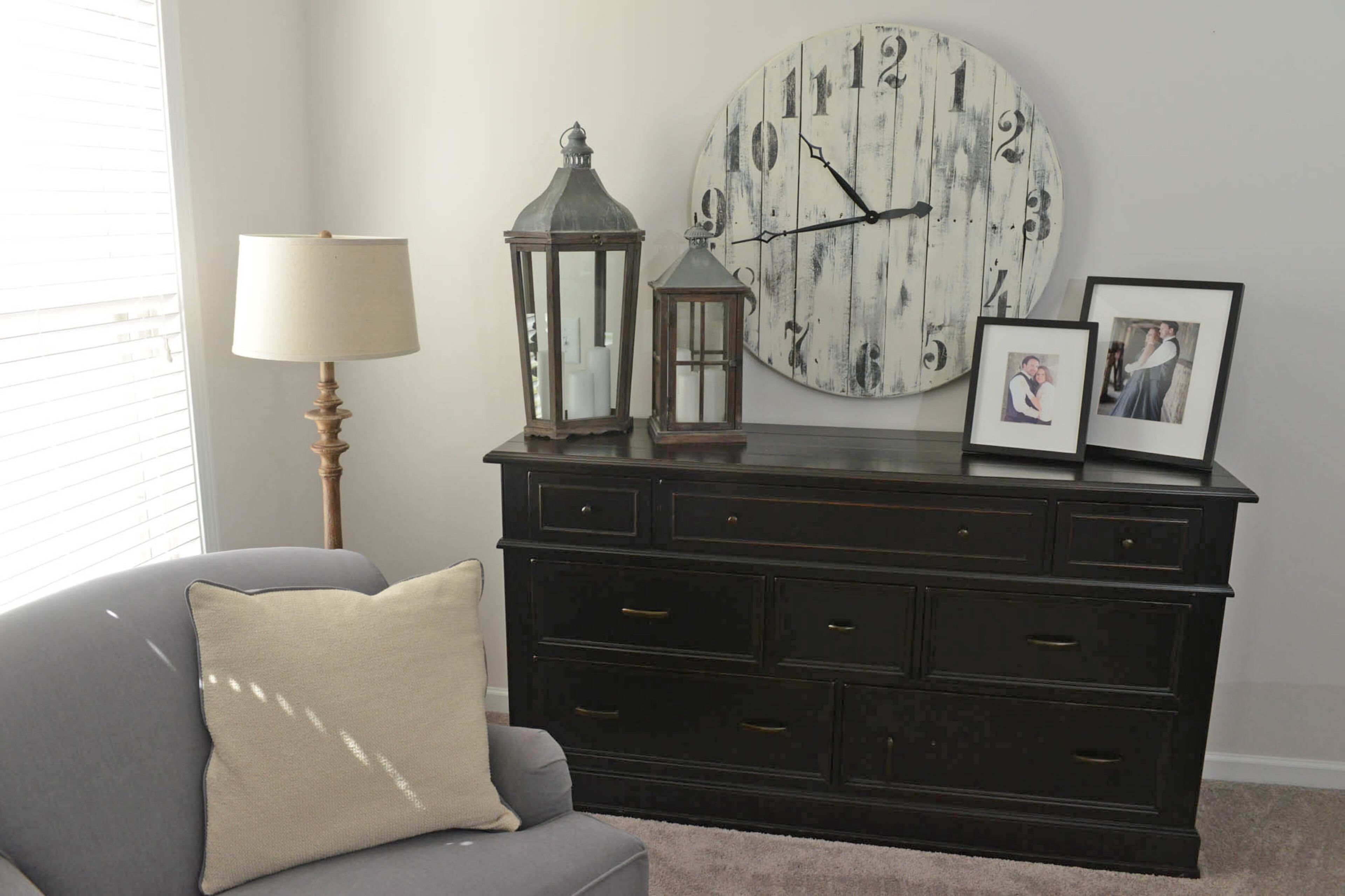 An oversized chair from Havertys and the armoire from Junque Yard Antiques in Columbus creates a cozy nook in the master bedroom. The distressed wall clock and decorative candlelit lanterns are from Woodstock Market.