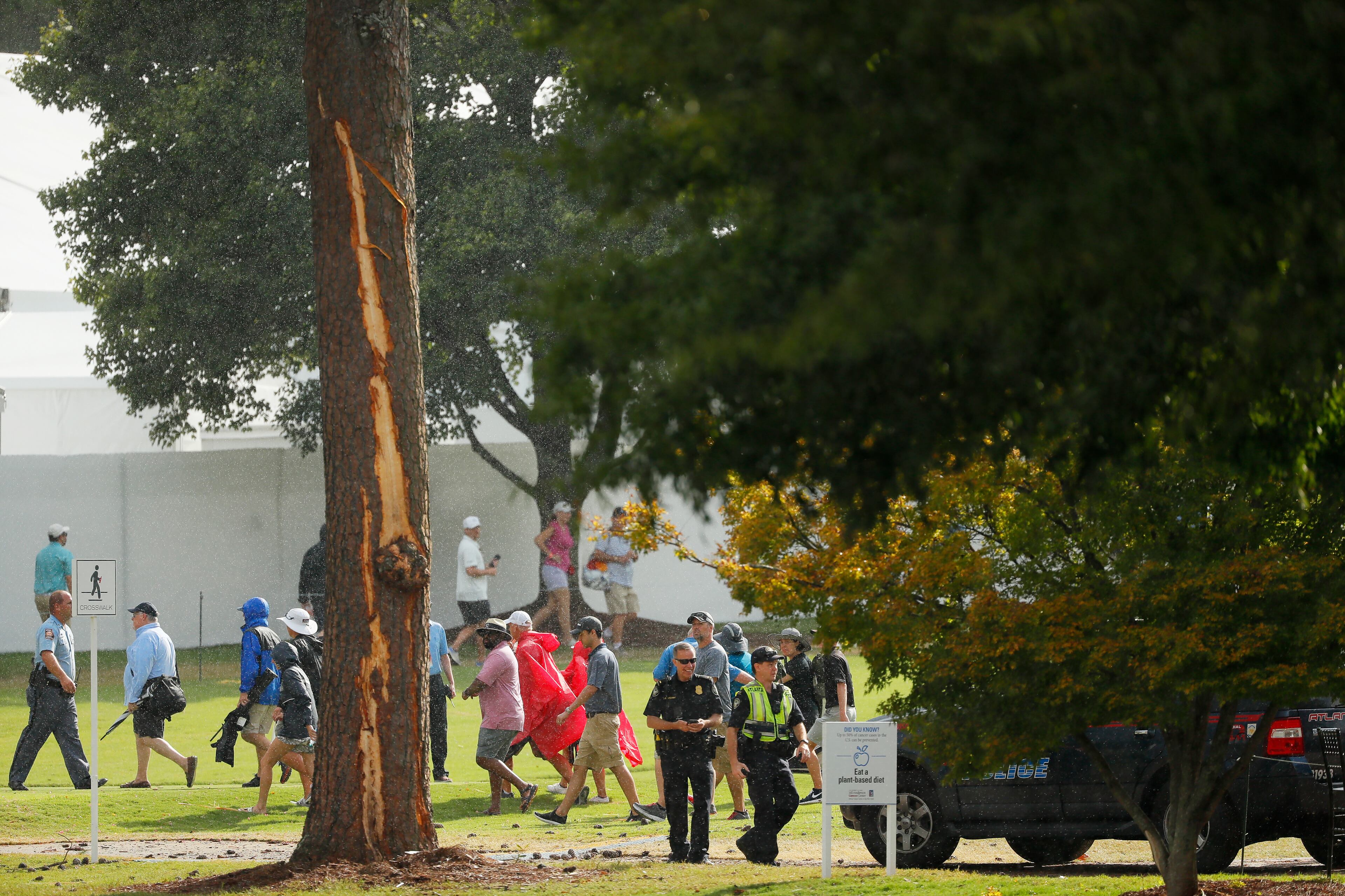 Police officers stand watch next to a tree damaged by a lightning strike during a suspension in play of the third round of the TOUR Championship at East Lake Golf Club on August 24, 2019 in Atlanta, Georgia. (Photo by Kevin C. Cox/Getty Images)